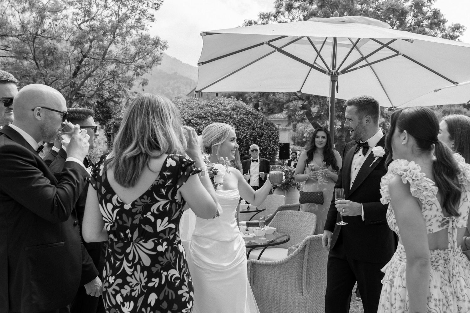 Wedding guests mingle and socialize on a patio during cocktail hour.