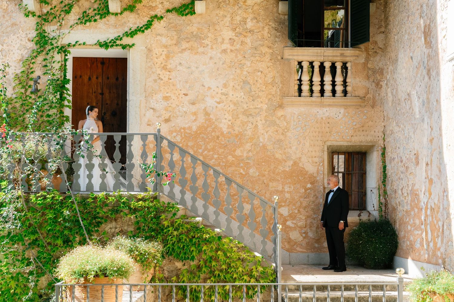 Rustic stone staircase with ornate balustrade decorated with climbing vines and greenery.