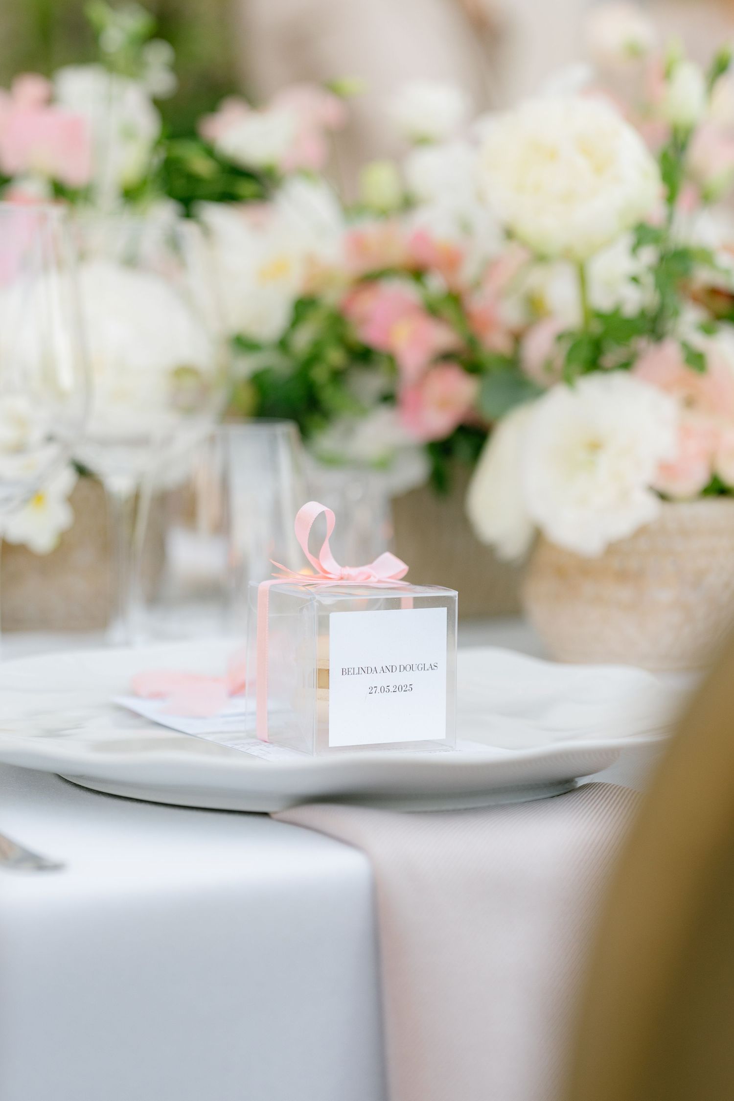 Elegant wedding table settings with pink and white floral centerpieces and name cards.