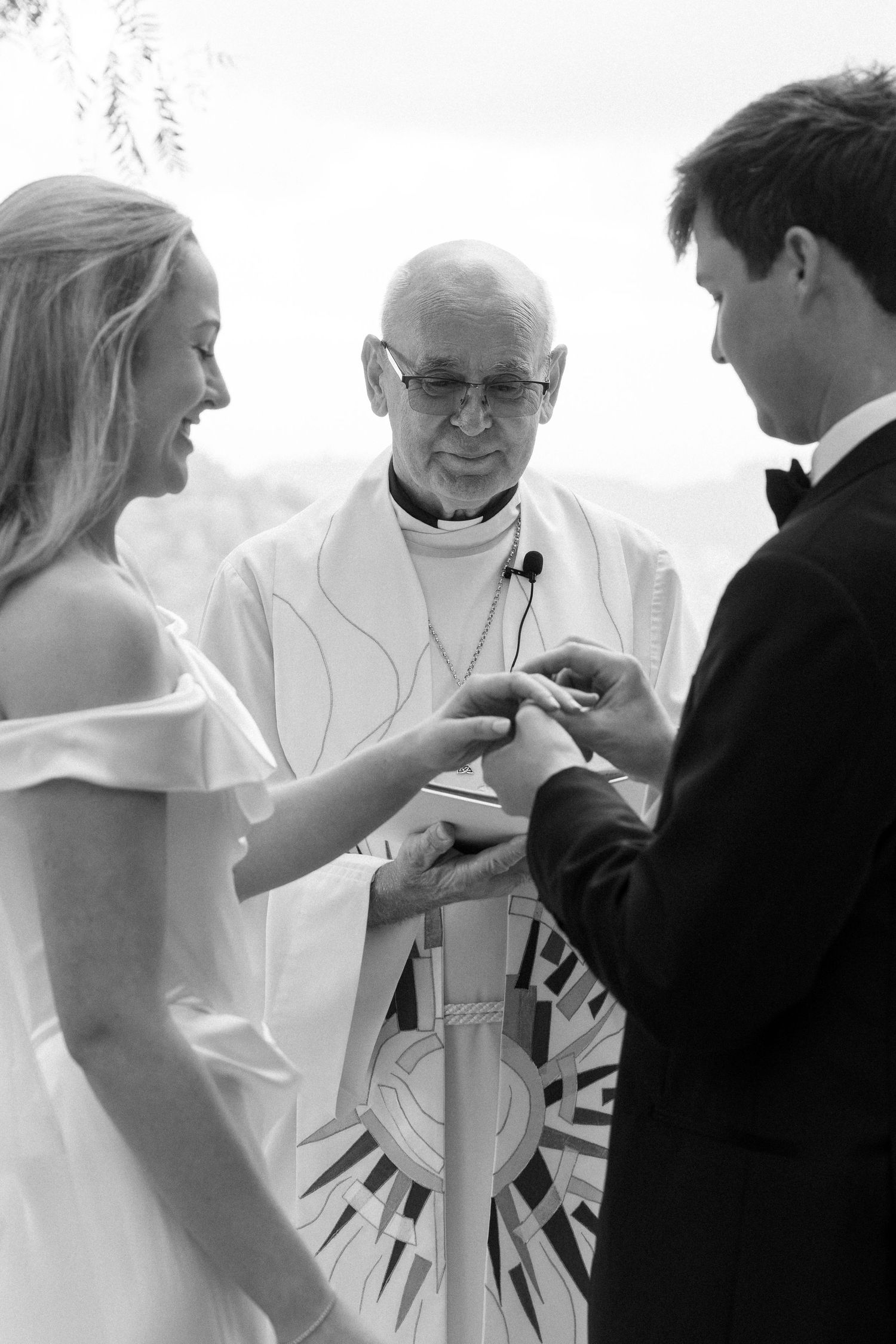 A traditional wedding ceremony moment captured in black and white with a religious officiant present.