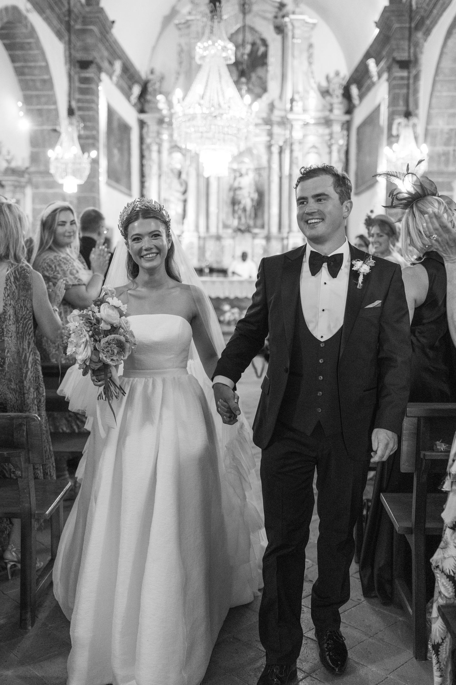 Wedding celebration in an ornate ballroom with crystal chandeliers overhead.