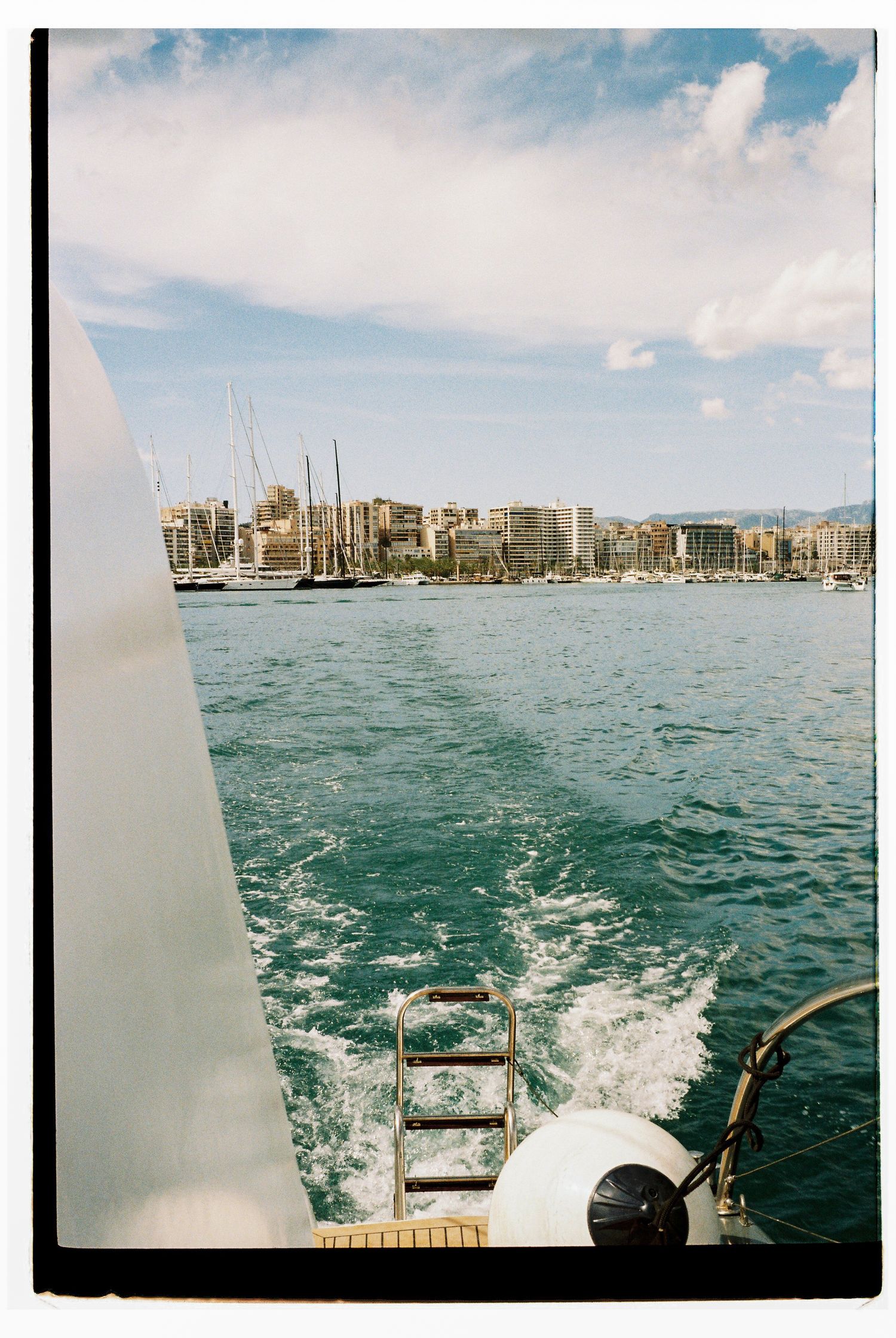 View from a boat showing the wake and Honolulu skyline across turquoise waters.