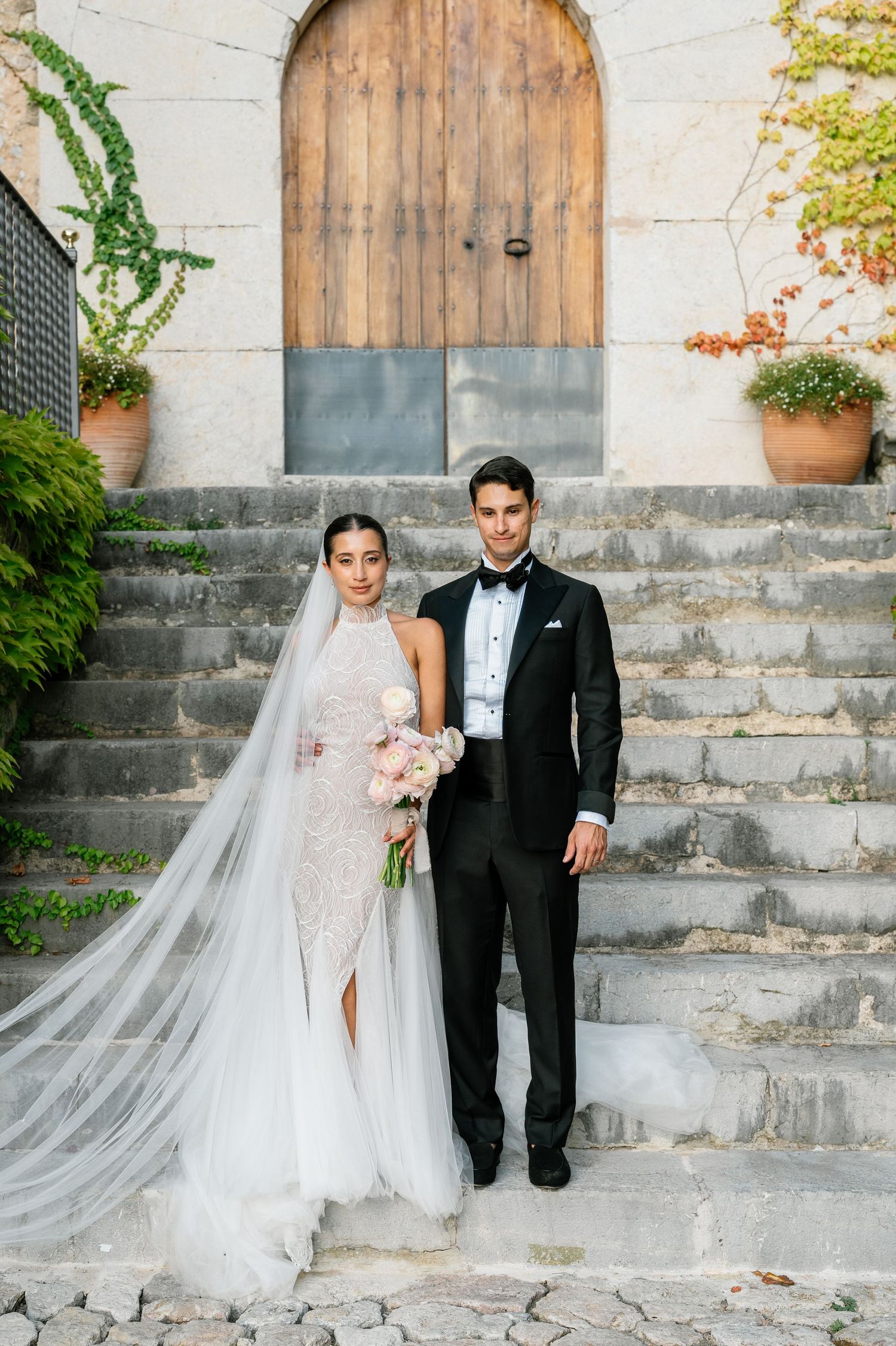 Wedding portrait session on rustic stone steps with wooden door backdrop.