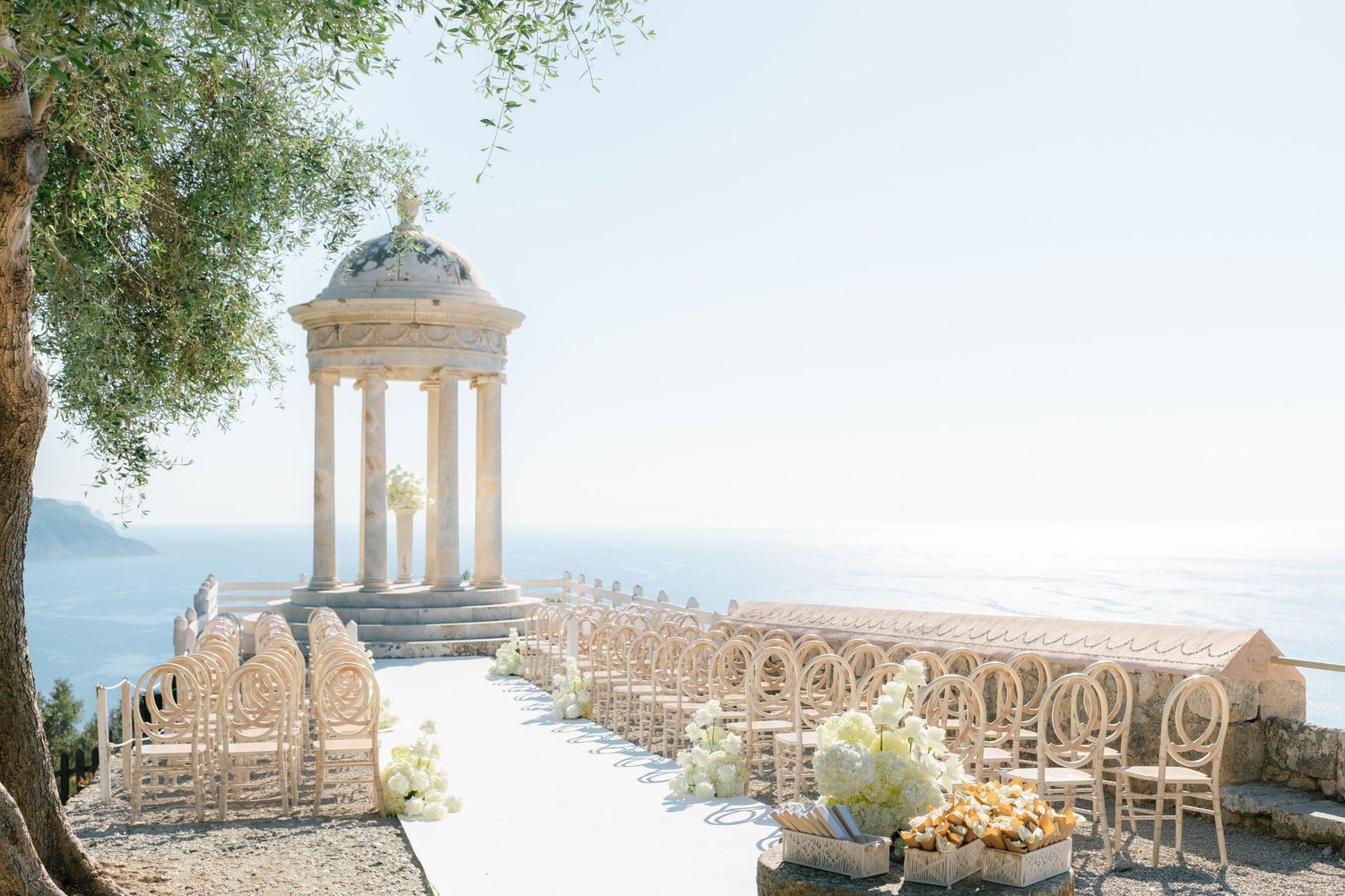 Elegant outdoor wedding venue with white columns and mountain views in Mediterranean setting.