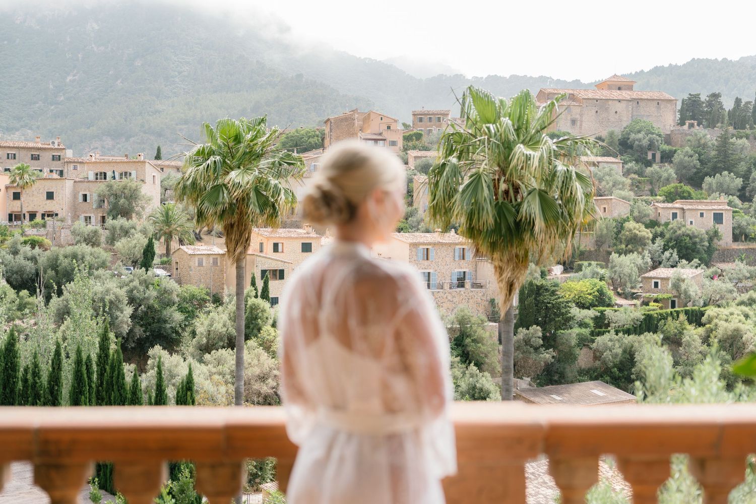 Scenic view of Mediterranean village with mountains and palm trees in background.