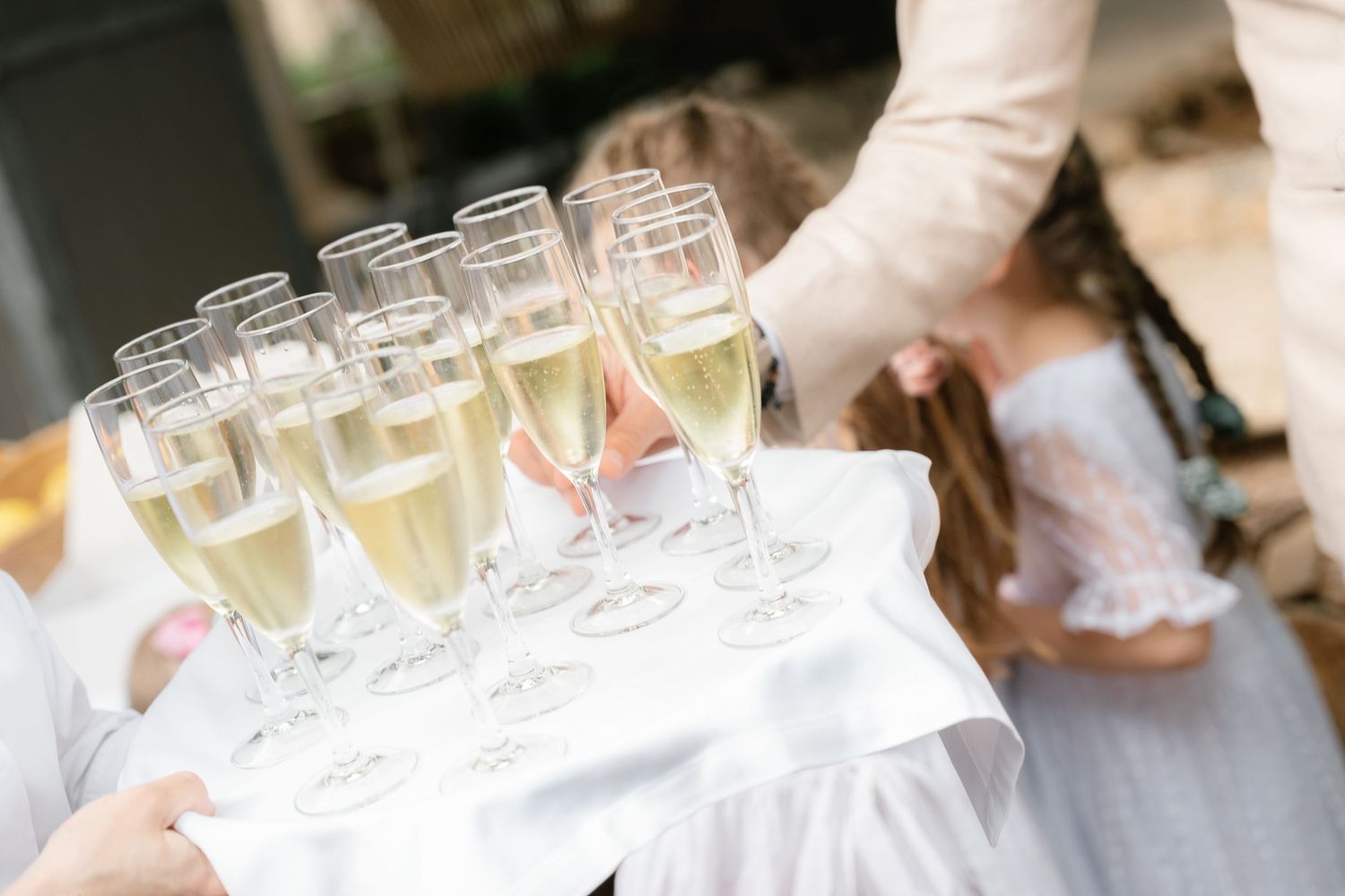 Row of champagne glasses lined up on a white tablecloth at an elegant event.