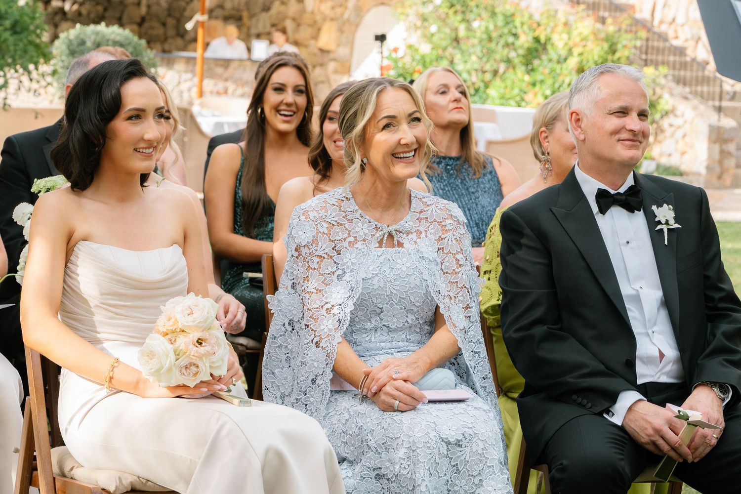 Wedding guests enjoying outdoor reception with laughter and conversation.