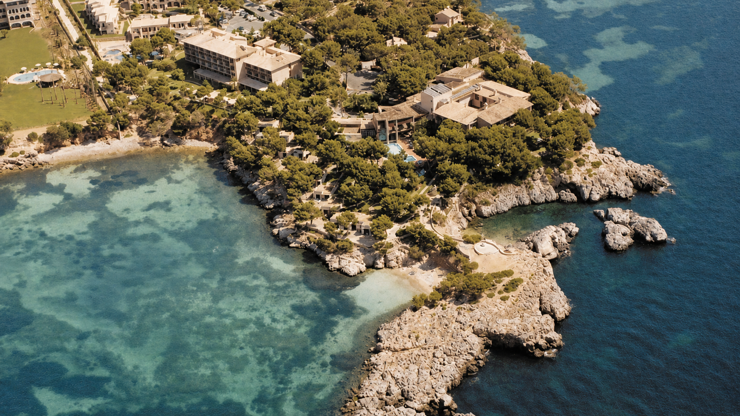 Mandarin Oriental. Aerial view of a luxury coastal resort on a rocky Mediterranean peninsula surrounded by crystal-clear turquoise waters.