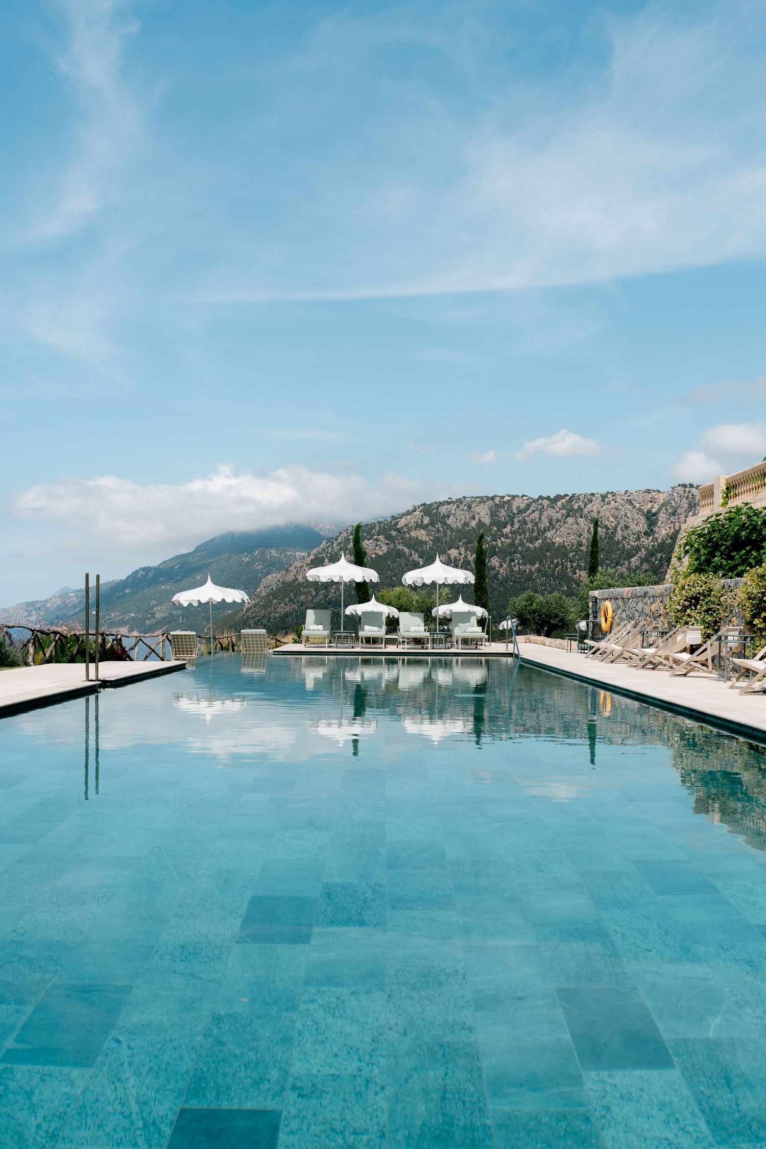 Stunning infinity pool with turquoise water reflecting mountain views and white parasols.