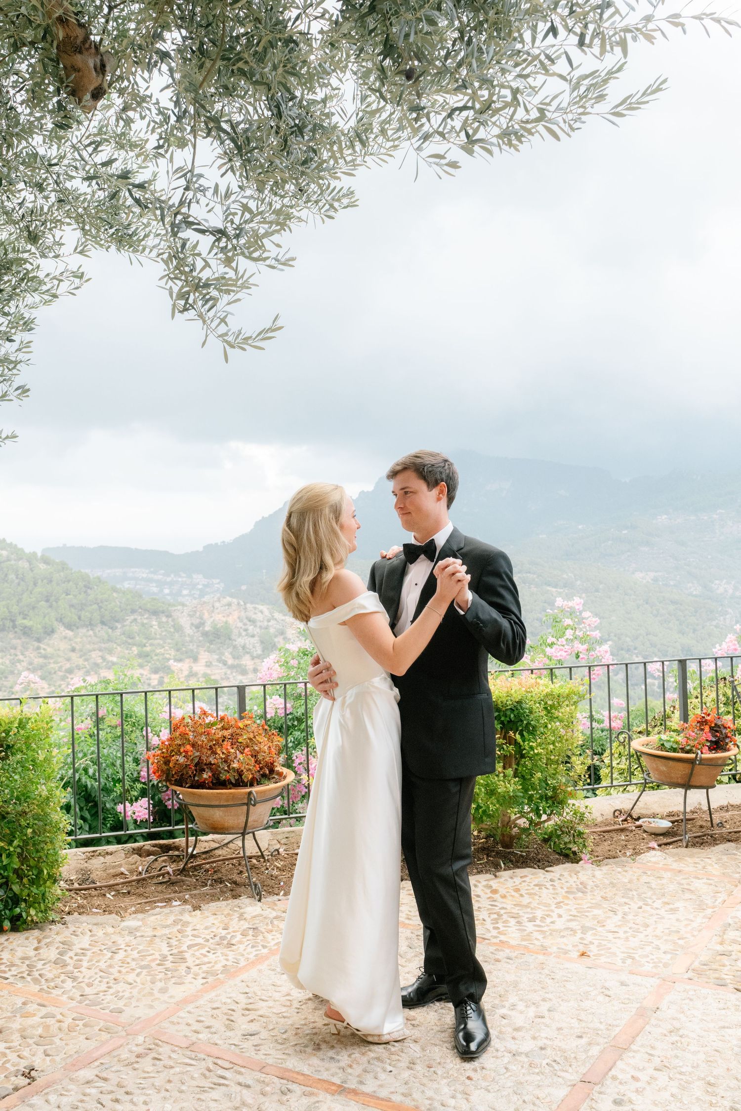 Couple shares romantic moment on scenic terrace overlooking Mediterranean landscape.