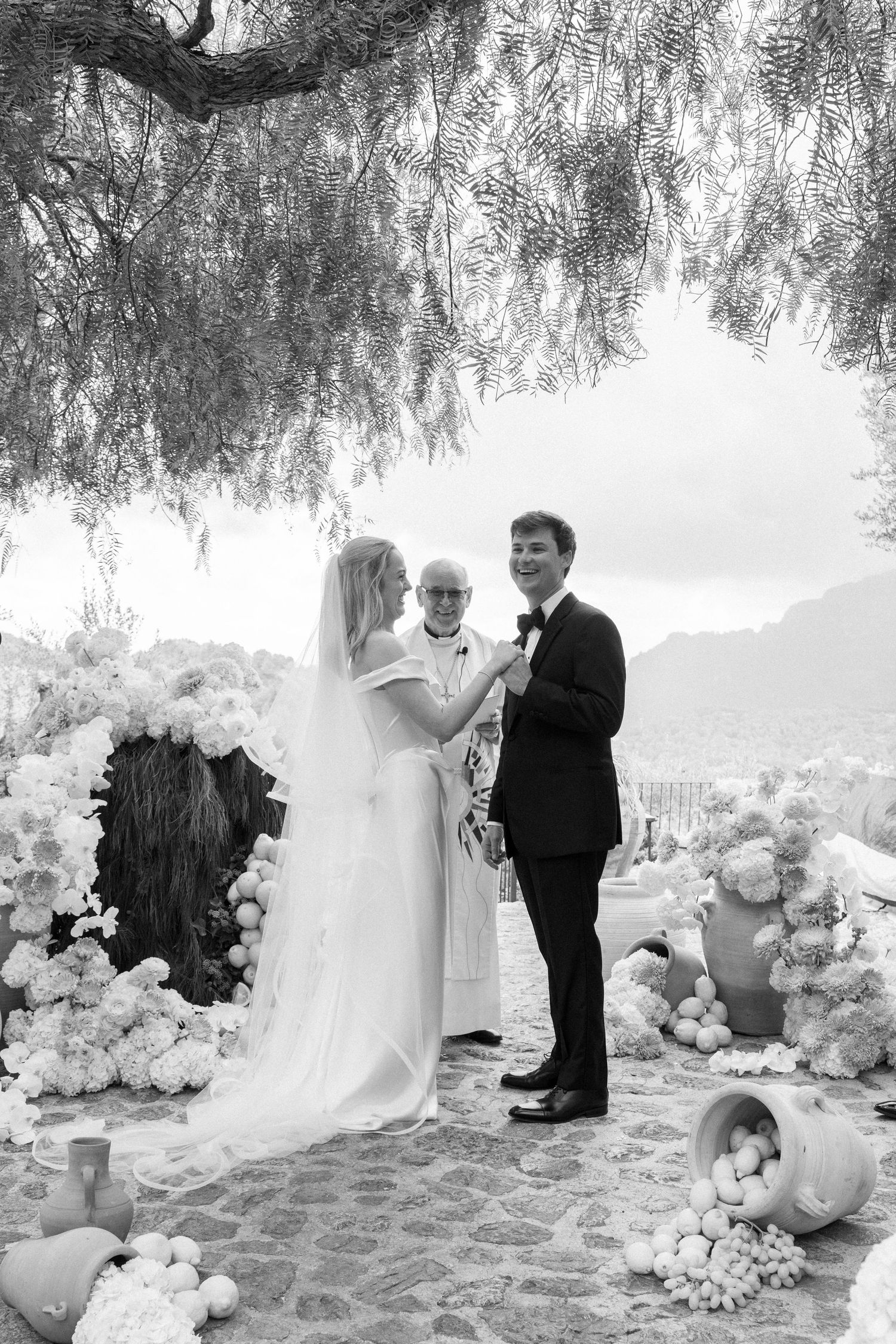 Black and white wedding photos show a couple on the beach surrounded by elegant floral arrangements.