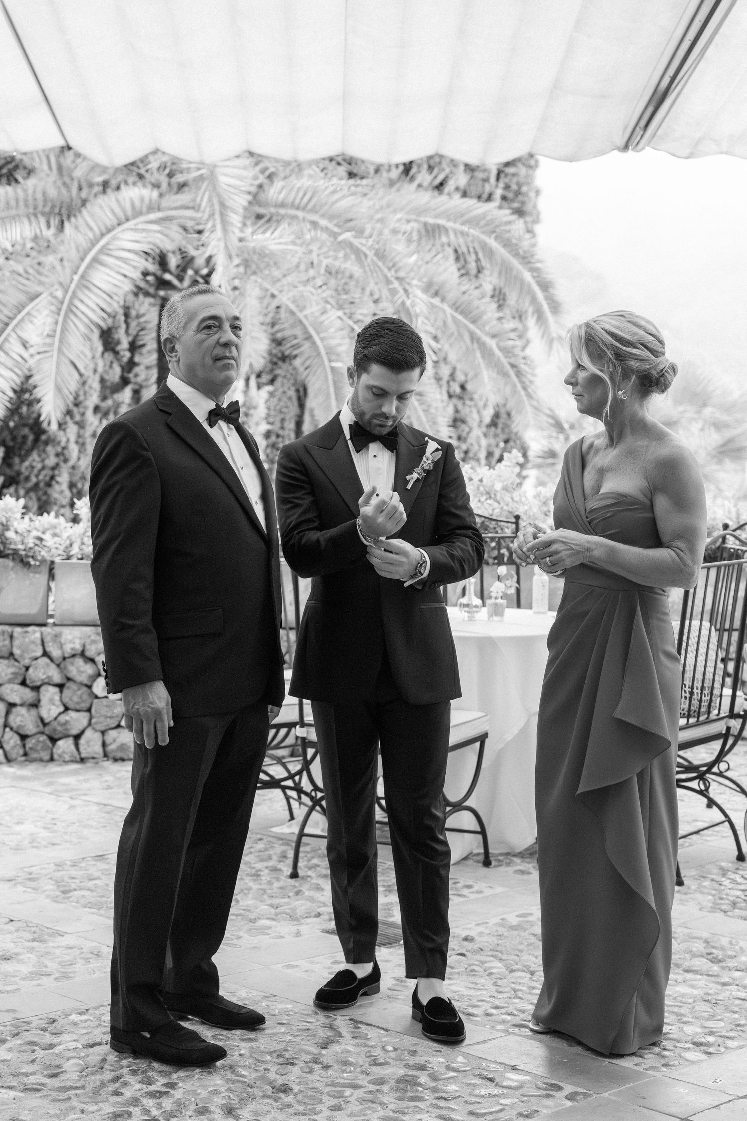 Black and white photos of wedding guests in formal attire interacting and laughing at an outdoor reception.