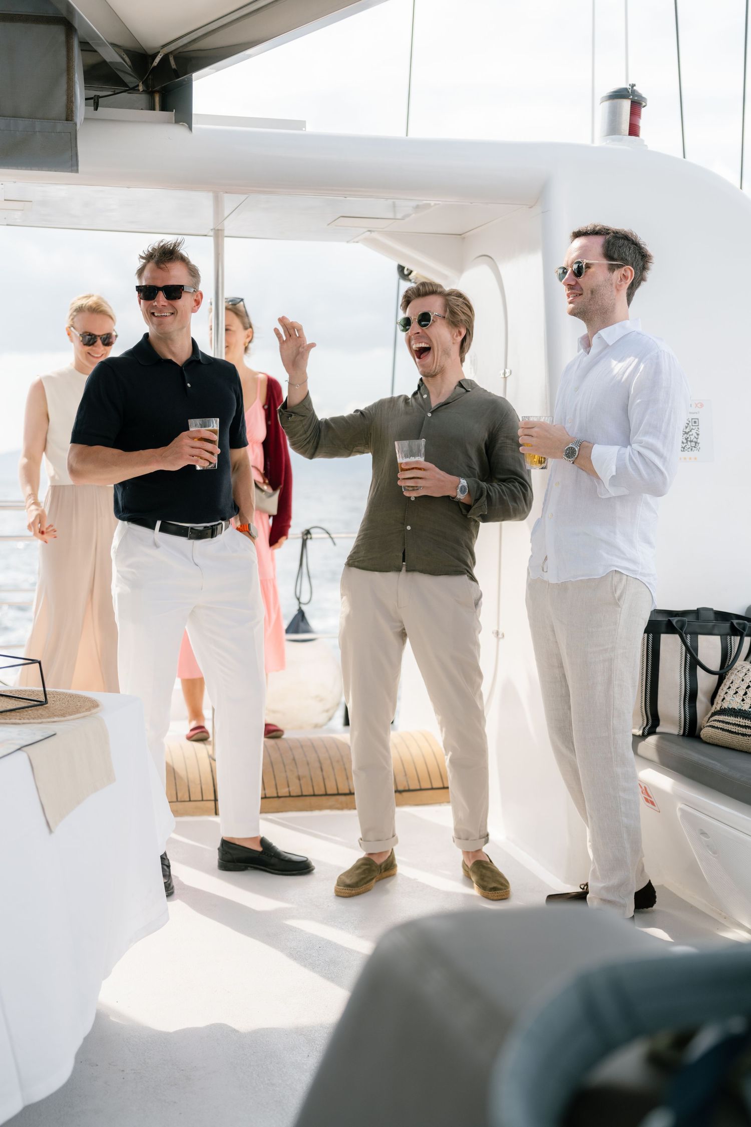 Guests mingling in white and neutral attire during an elegant boat gathering.