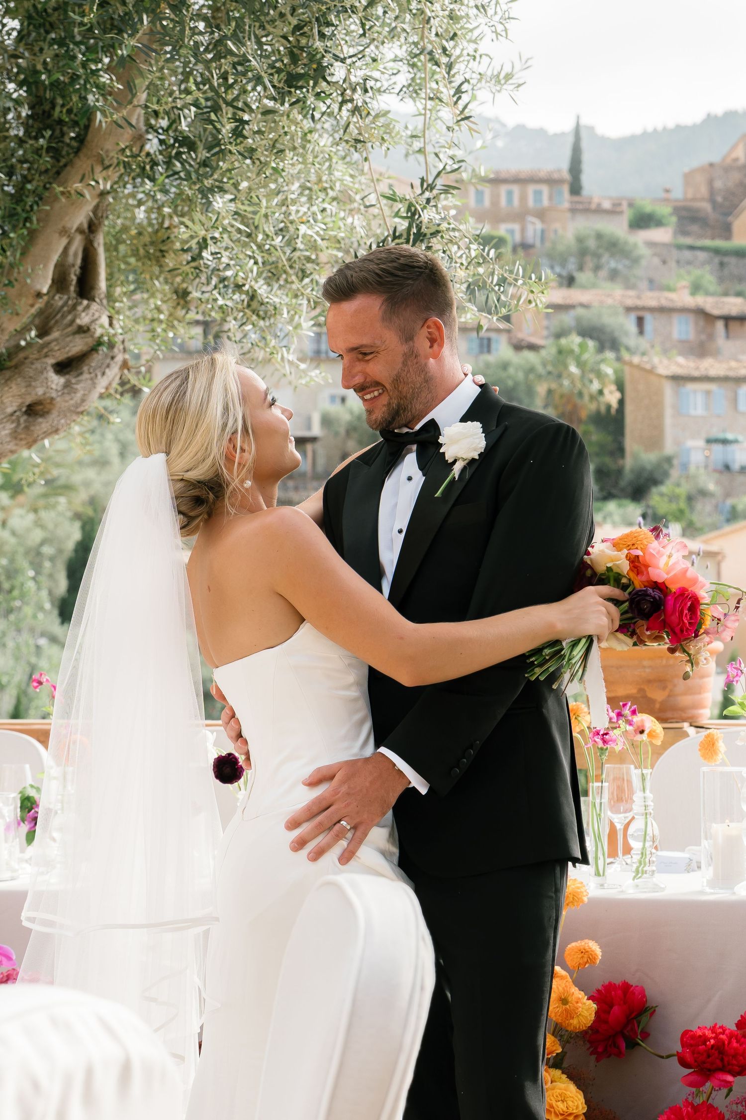 Romantic wedding couple sharing intimate moments against a Mediterranean hillside backdrop.