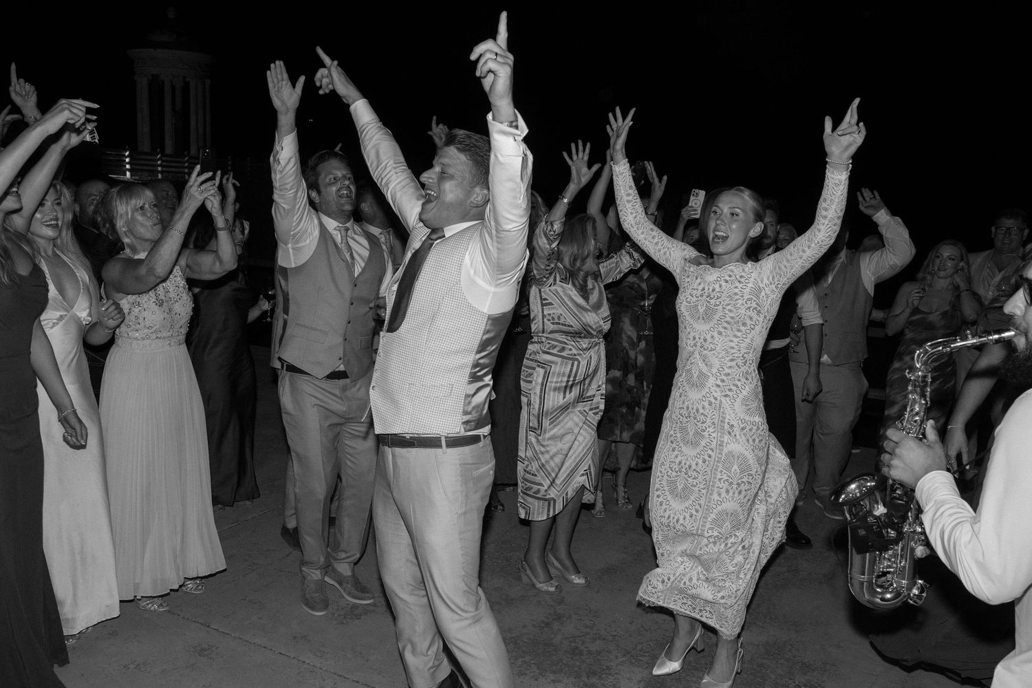 Energetic crowd dancing with hands raised at a nighttime celebration.