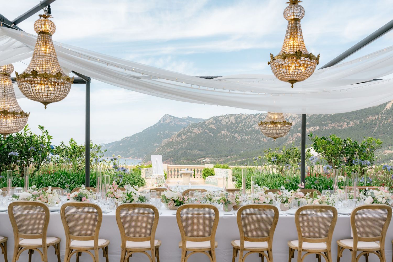 Wedding reception tables set under crystal chandeliers with stunning mountain vistas.