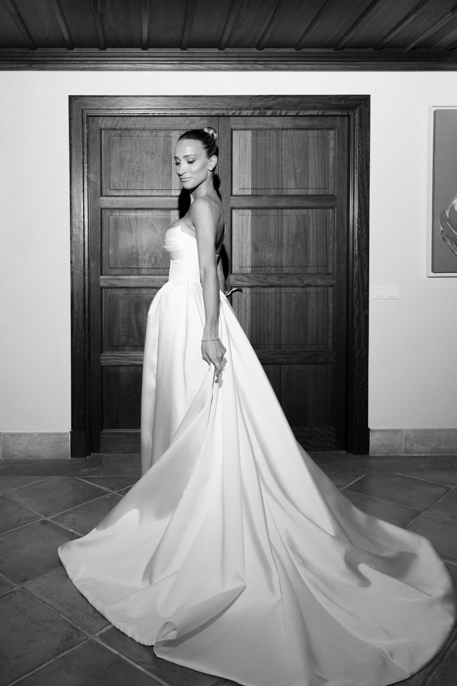 A bride in a flowing white wedding gown with a dramatic cathedral train poses in a series of elegant black and white photos.