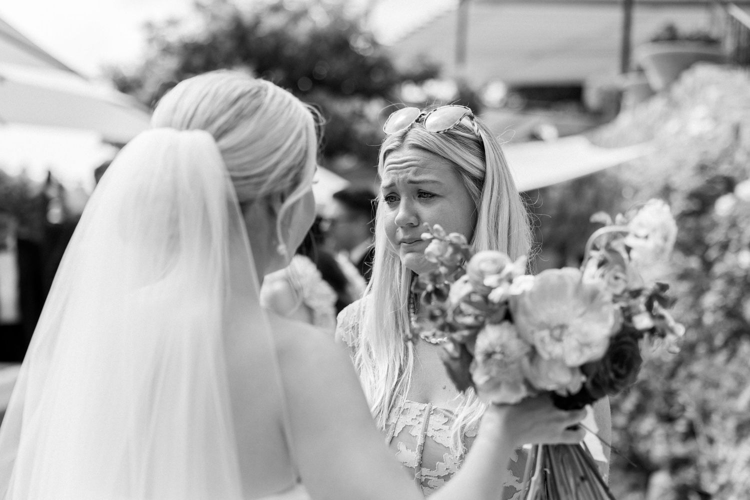 Wedding party members laugh and celebrate during an outdoor cocktail reception.