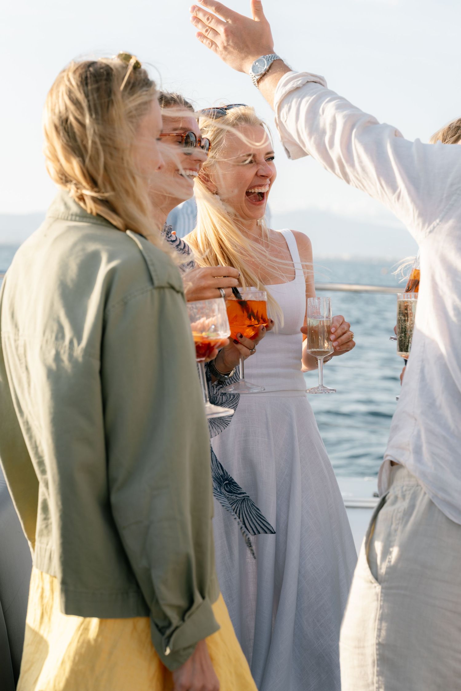 Guests in white and sage attire celebrating at a seaside gathering.