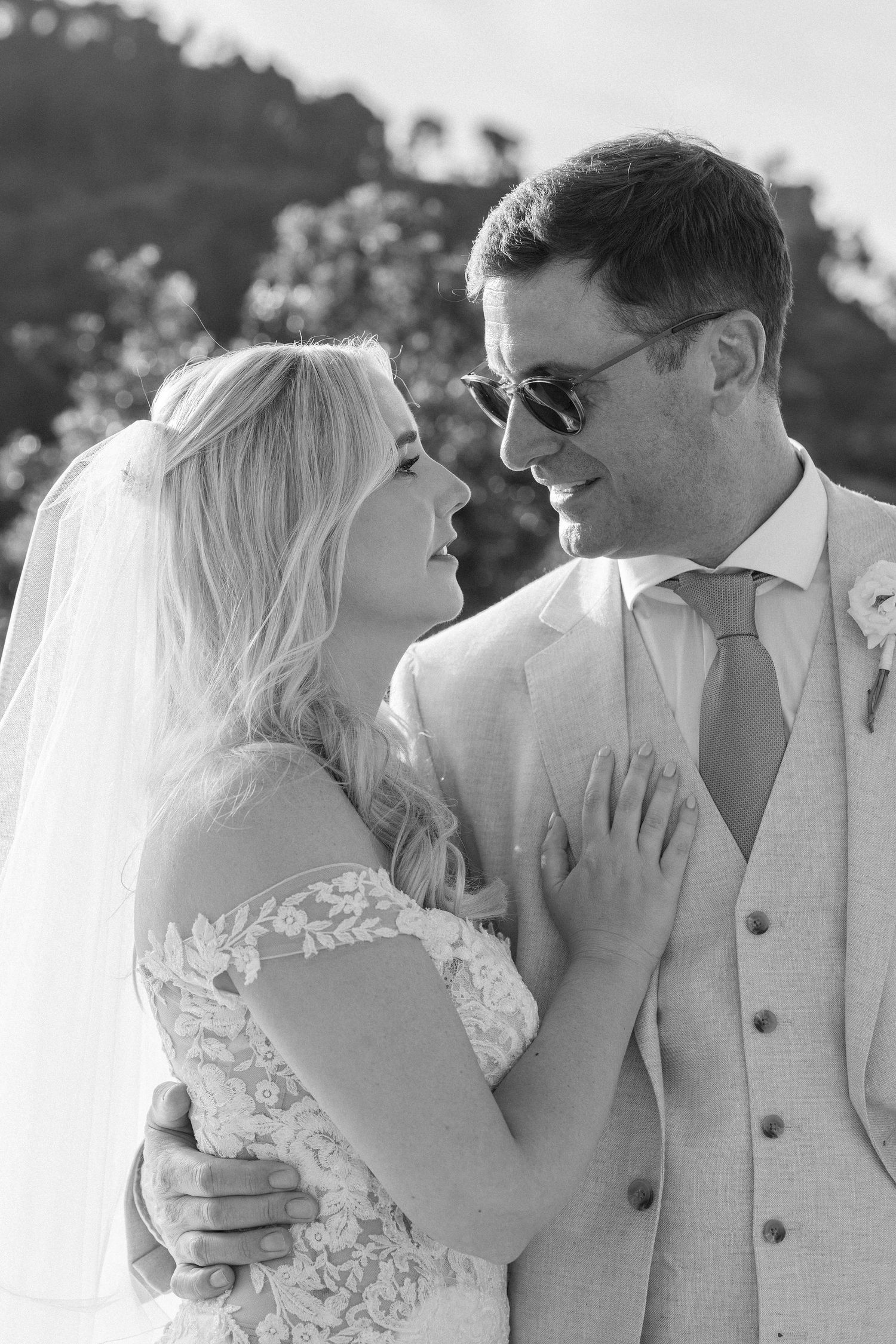 Close up black and white portrait of newlyweds sharing an intimate moment in sunlight.