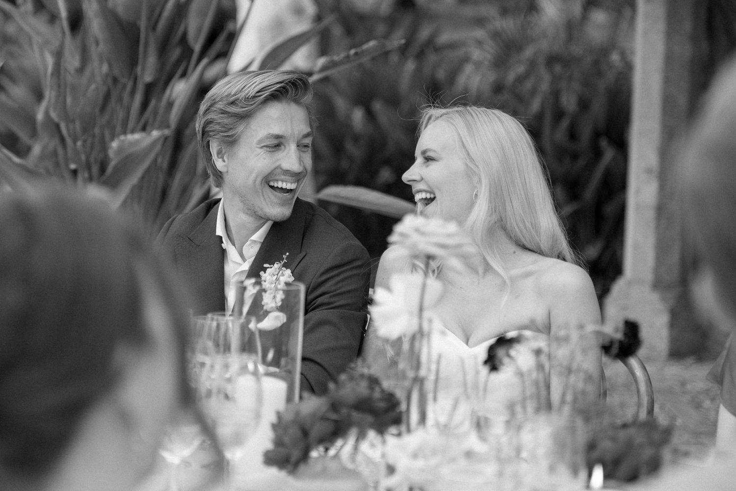 Black and white candid photo of a couple sharing a joyful moment at an elegant dinner party.