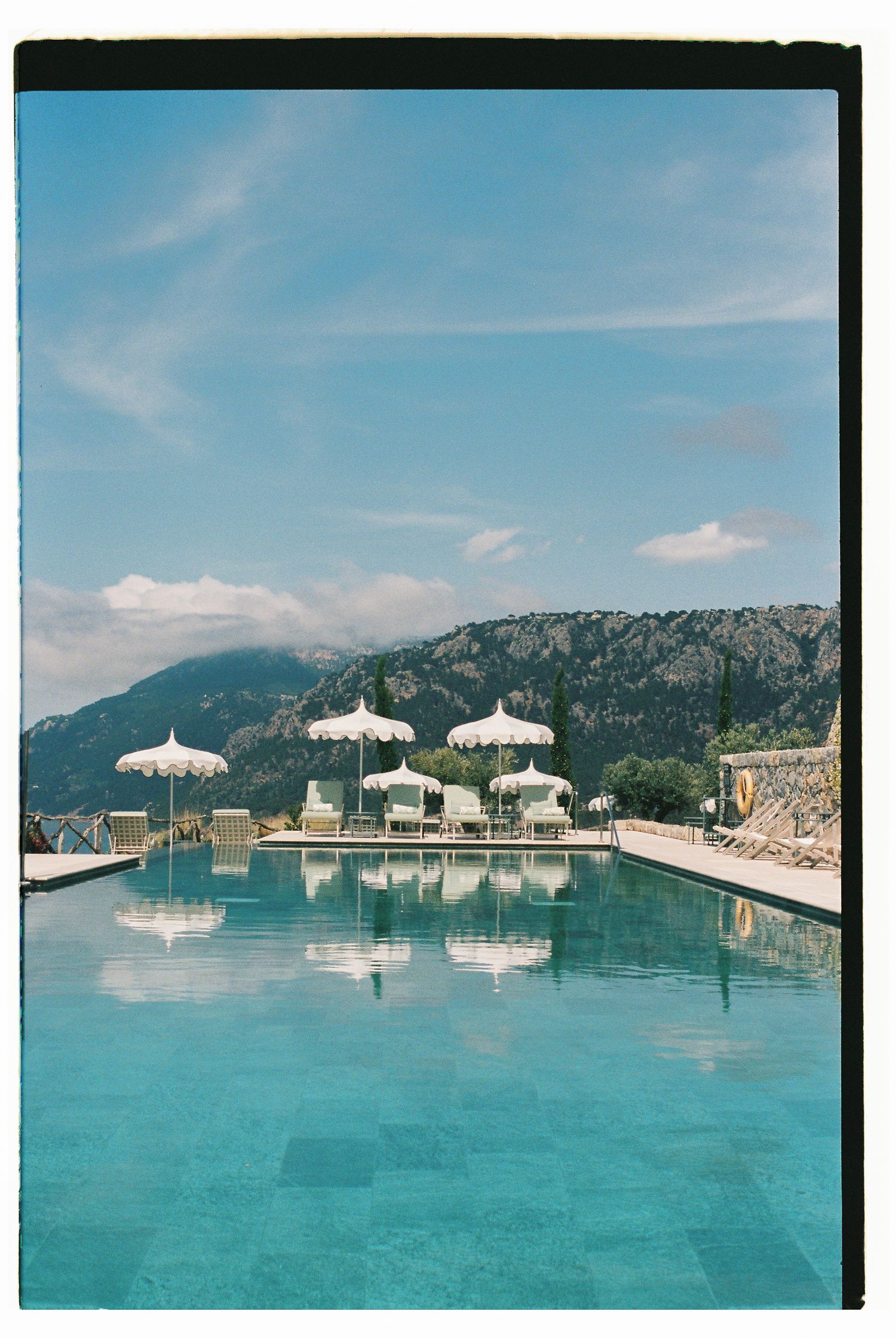 Luxurious infinity pool with white umbrellas overlooking scenic mountain views at an upscale resort.