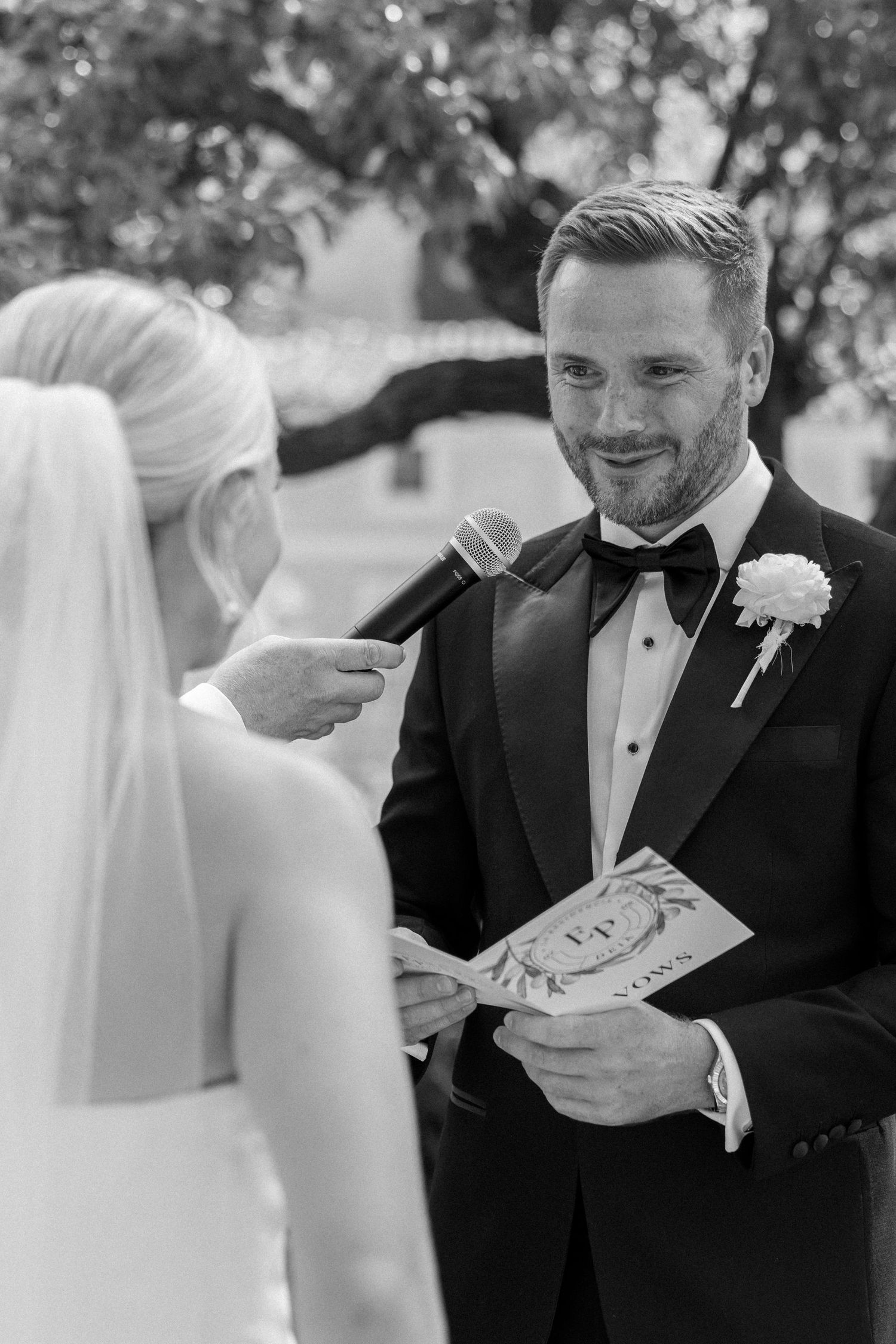 Black and white moment of couple exchanging vows during wedding ceremony.