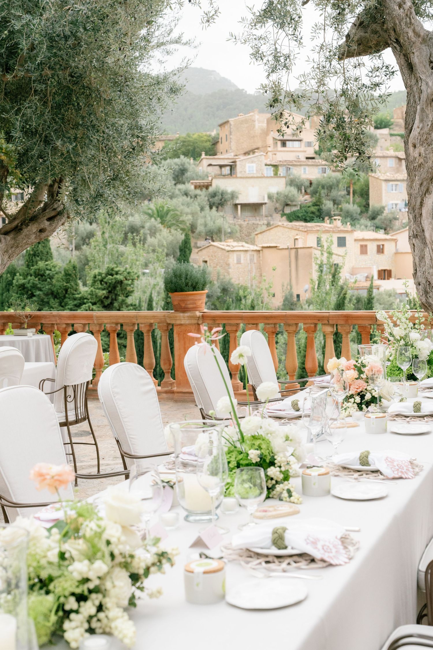 Outdoor wedding reception tables set with white linens and floral centerpieces overlooking scenic view.
