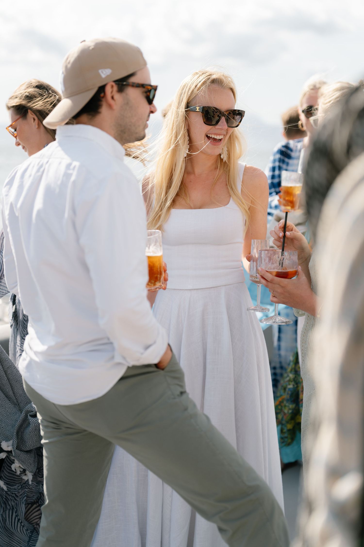 Guests in summer attire mingling at an outdoor celebration with drinks in hand.