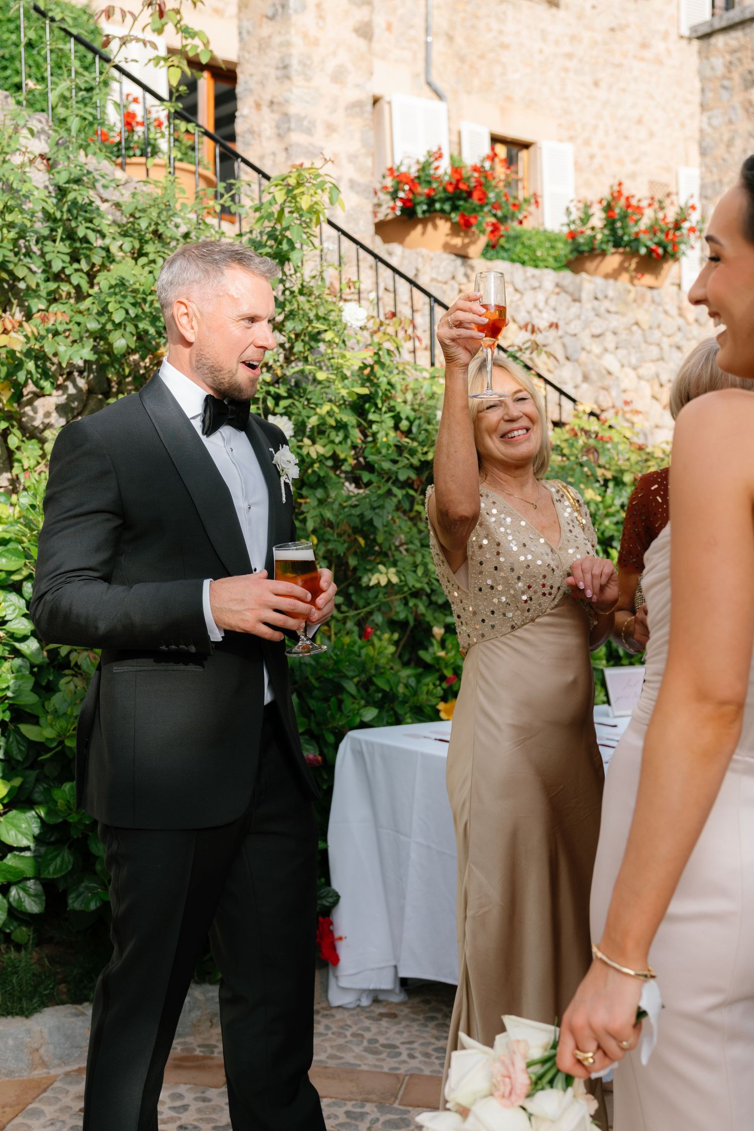 Wedding party members share joyful laughter during outdoor celebration in elegant formal attire.