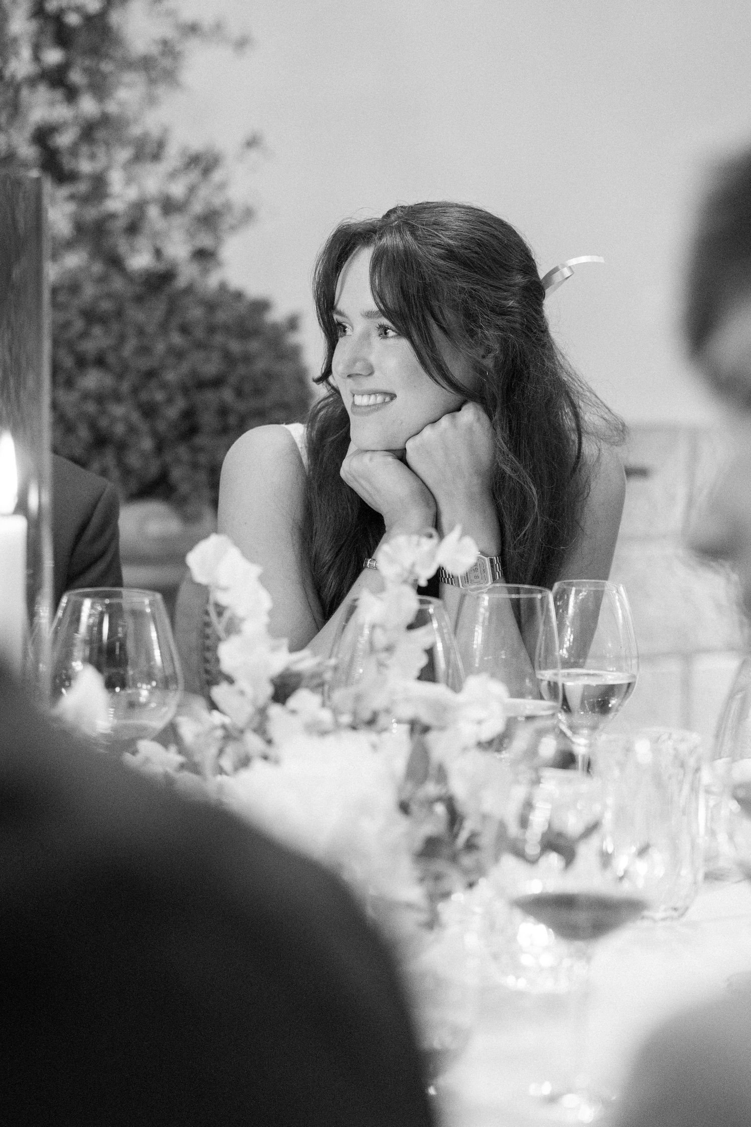 Wedding reception guests seated at decorated table with white floral arrangements.