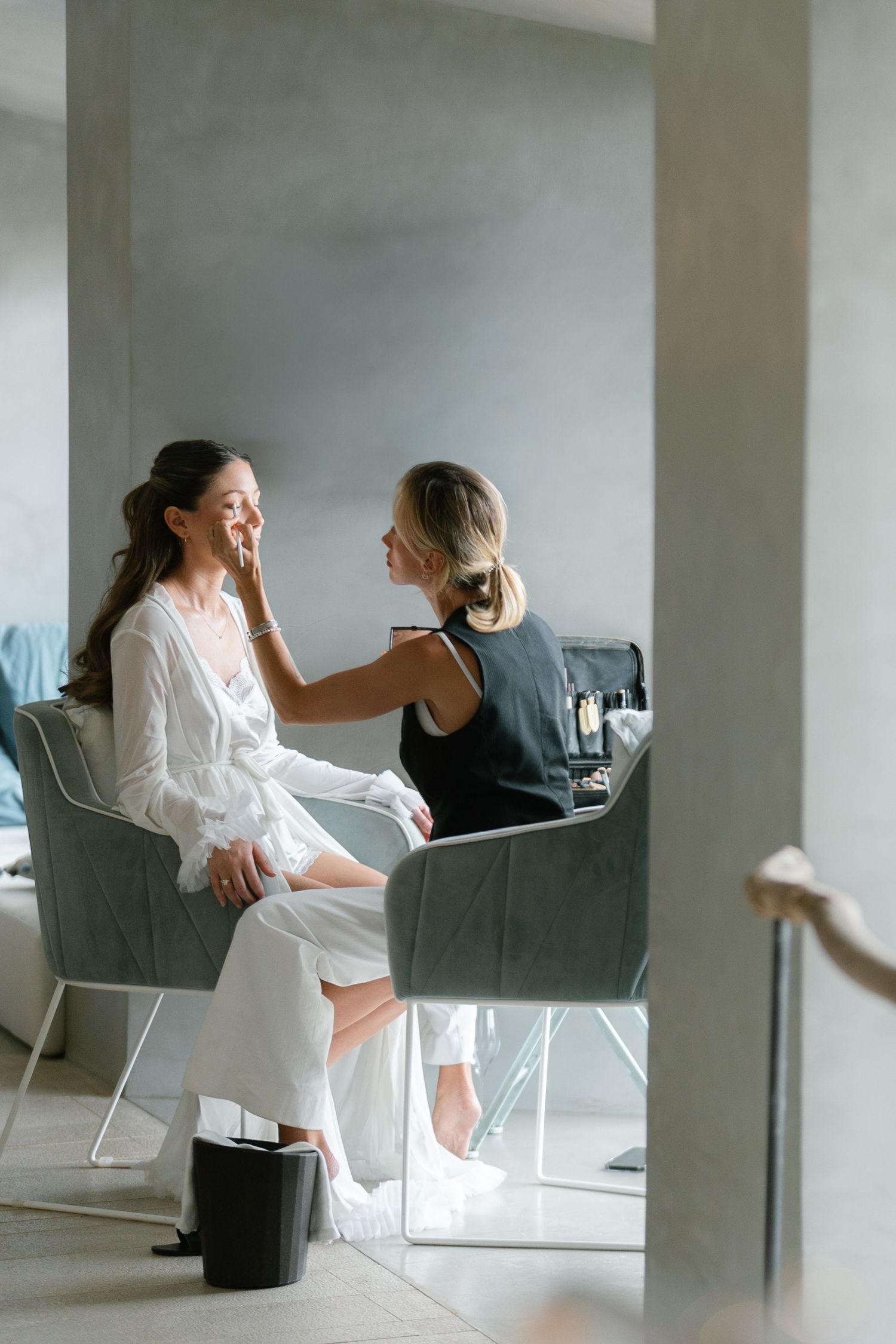 Wedding preparation scene in a modern white room with minimal furniture.