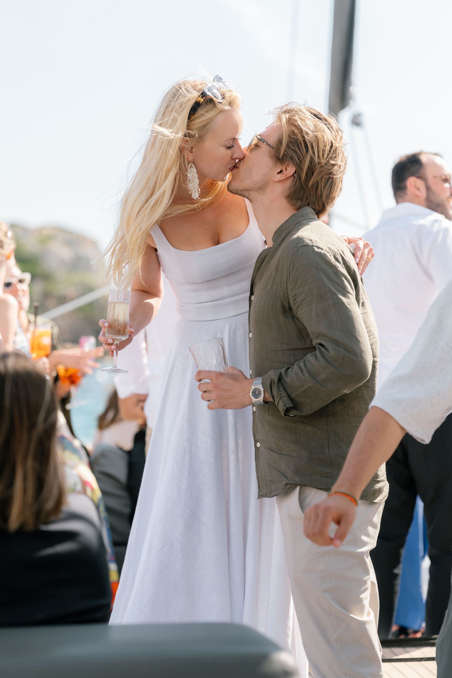 Couples in summer attire sharing intimate moments at a boat party.
