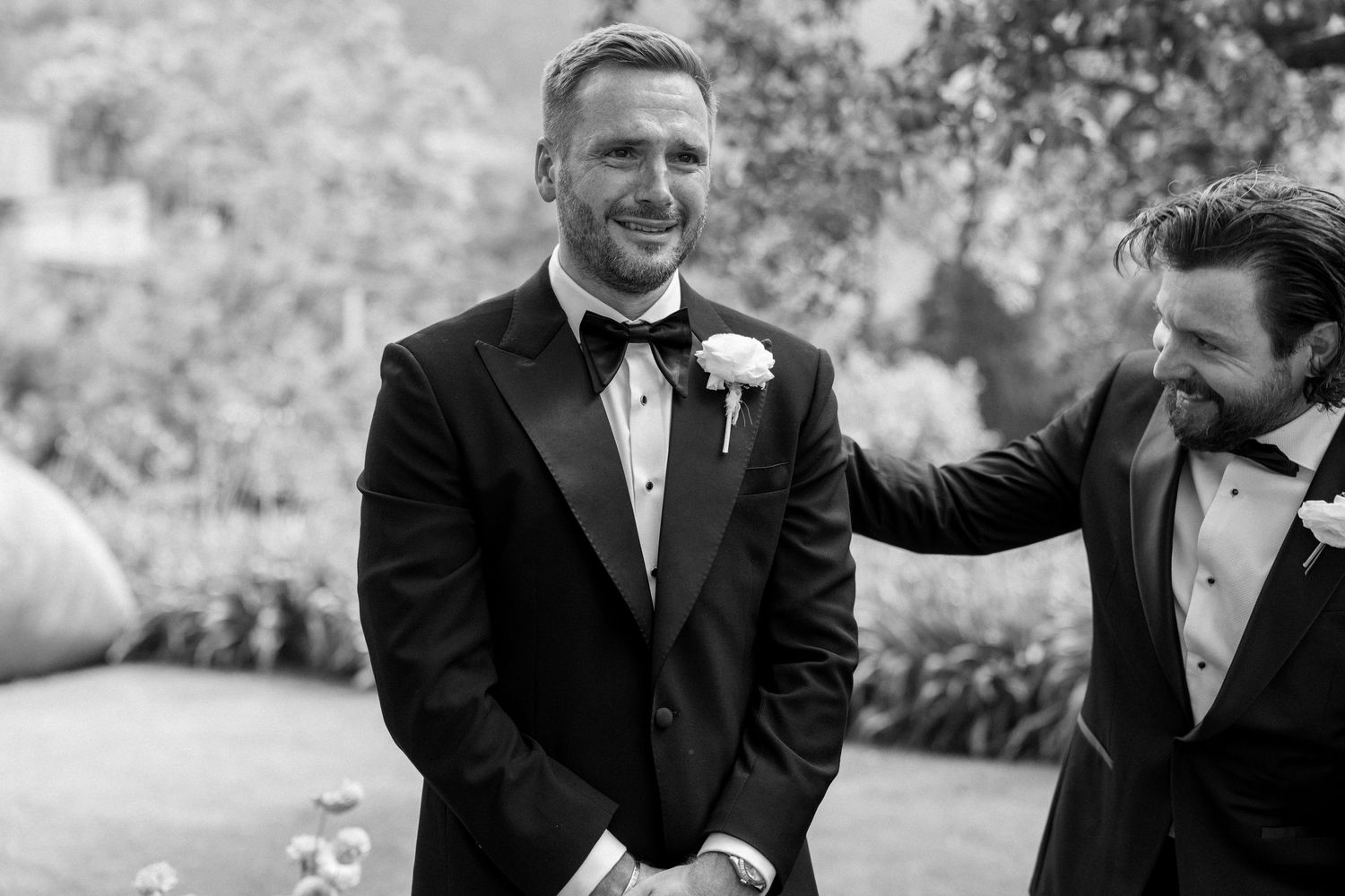Candid moments of groomsmen laughing during outdoor wedding ceremony.