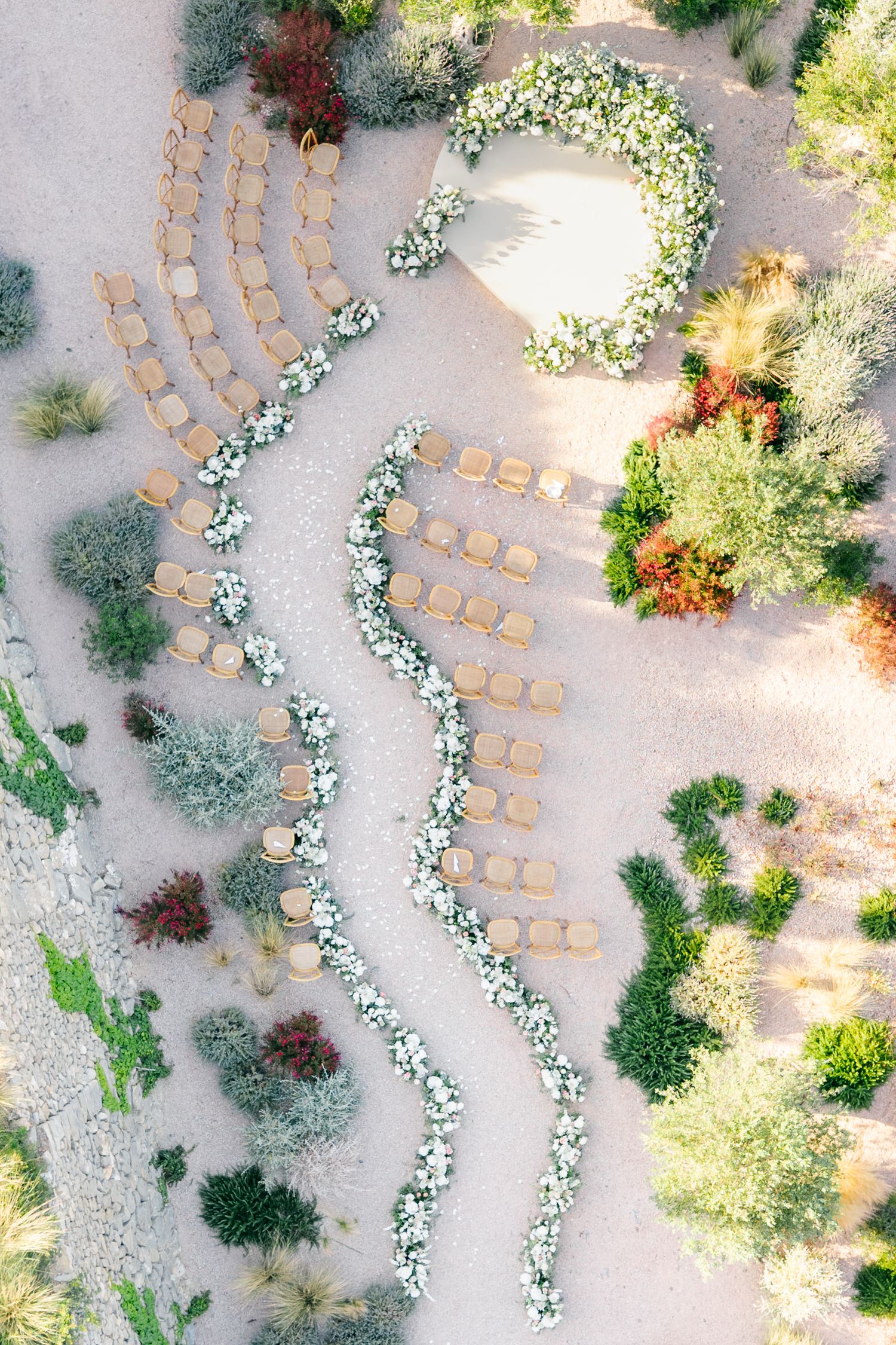 Aerial view of outdoor wedding ceremony setup with curved rows of chairs and floral arrangements.
