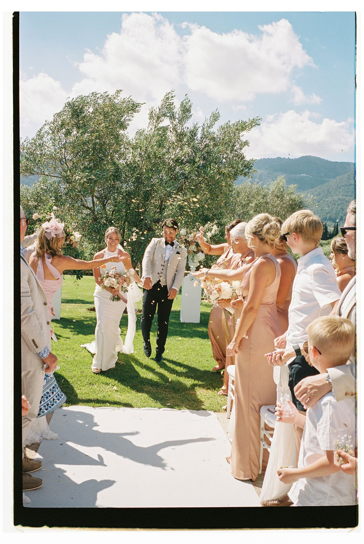 Wedding guests celebrating outdoors on a sunny day with mountain views.