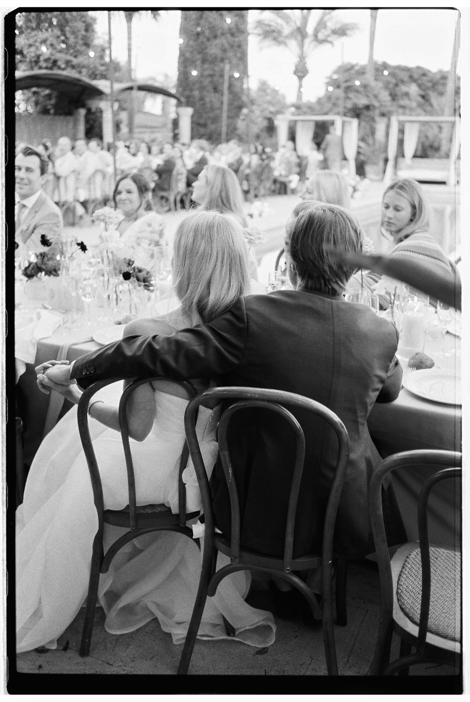 Wedding guests seated at reception tables during outdoor celebration.
