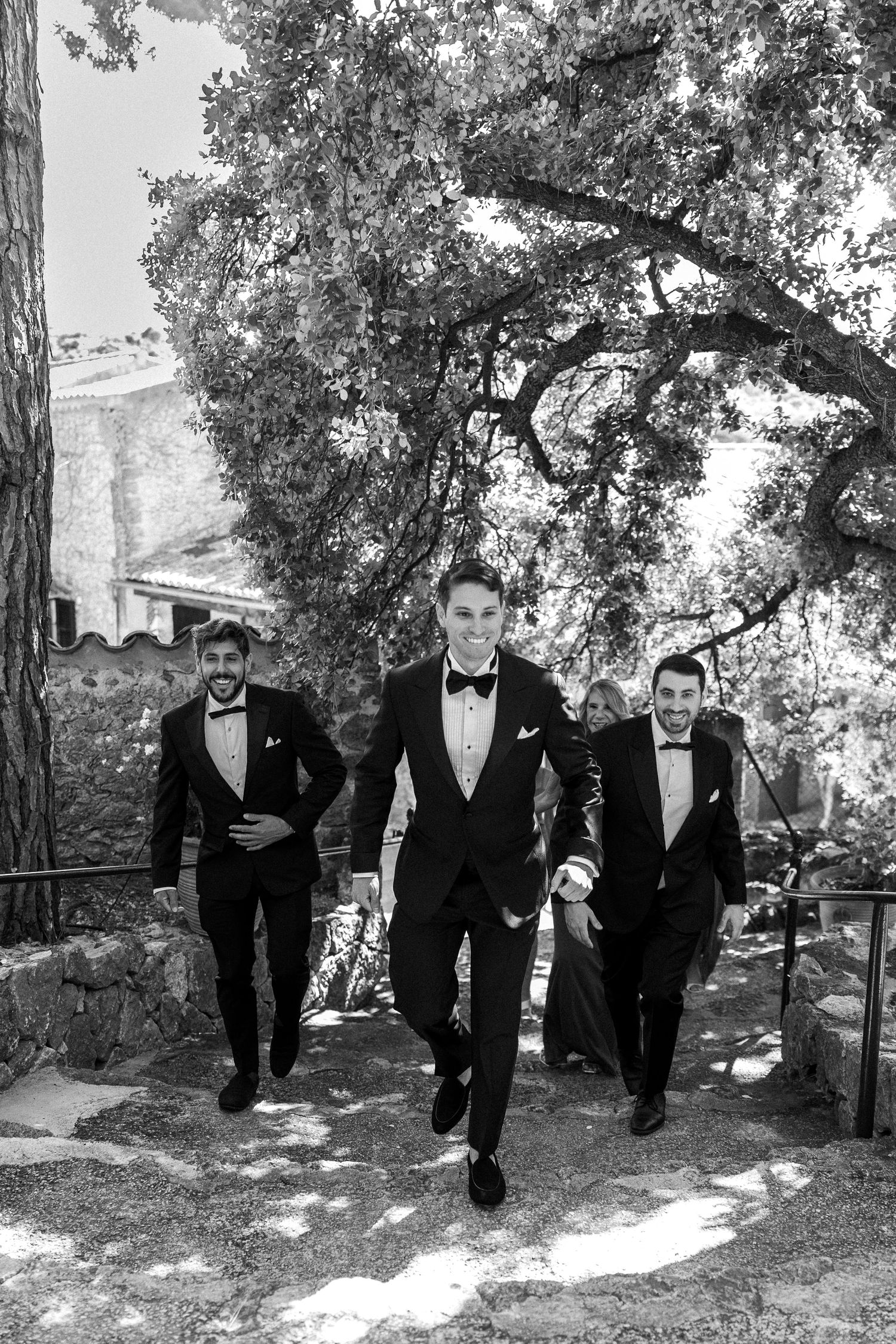 Three groomsmen in black tuxedos walk together outdoors in a sequence of candid shots.