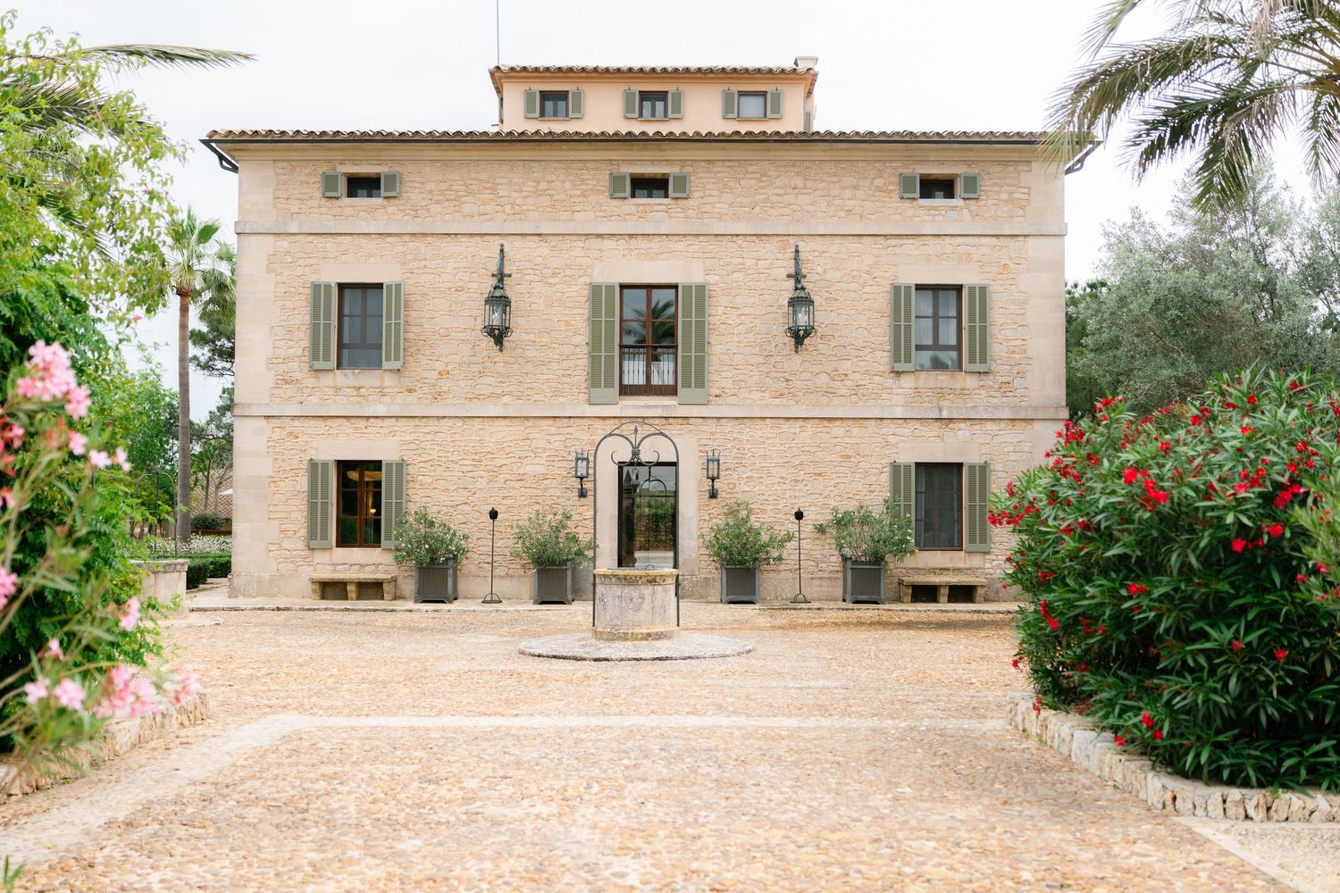 Mediterranean style villa exterior with palm trees and stone facade in warm sunlight.