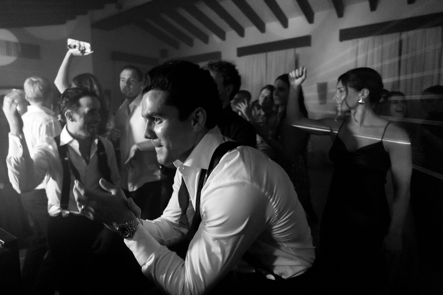 Dark atmospheric photos capturing wedding reception guests dancing and celebrating in a dimly lit venue.