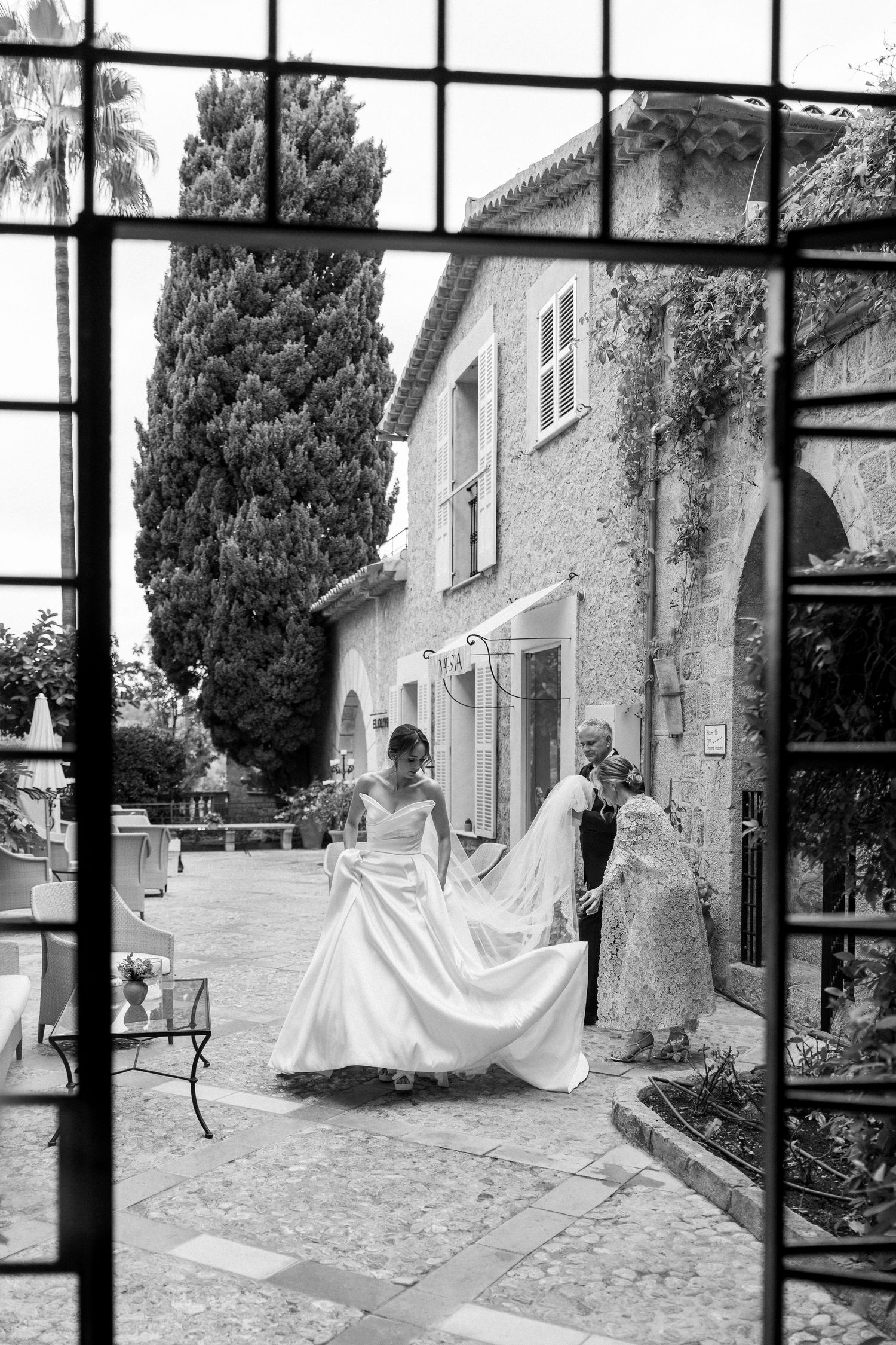 White wedding dresses hanging on display in a Mediterranean stone courtyard.