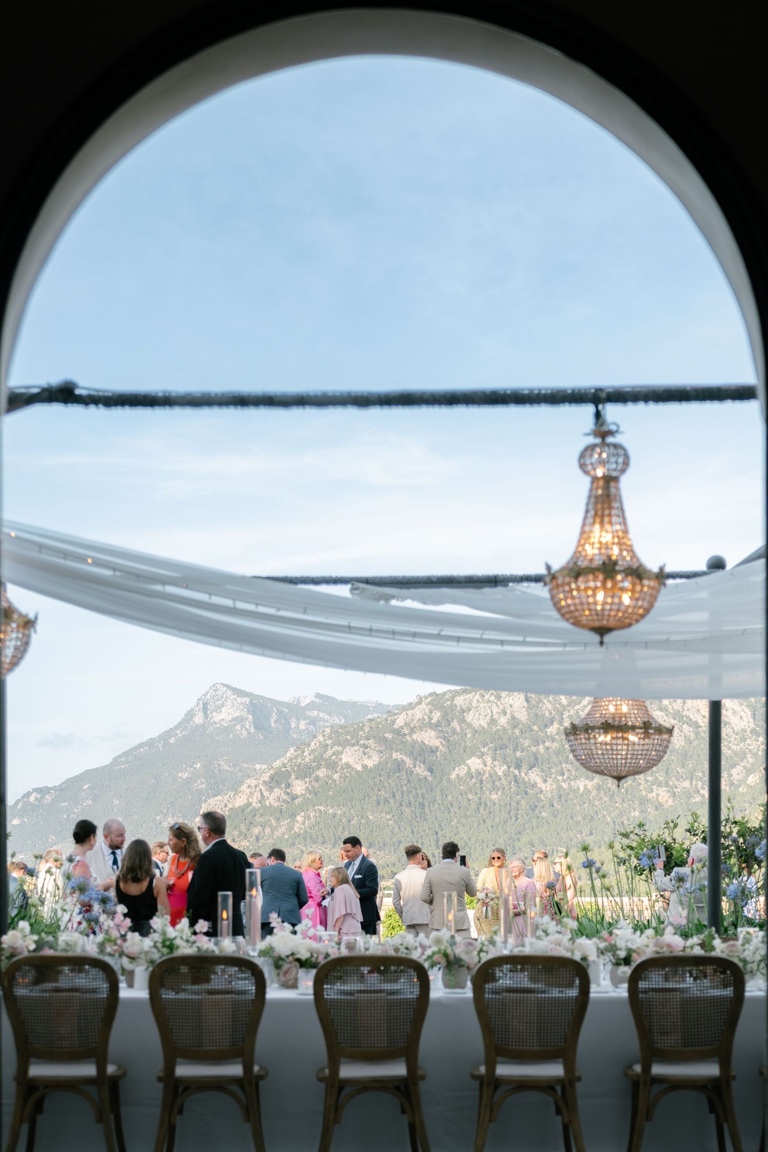 Elegant reception hall with arched windows, crystal chandeliers, and mountain views.