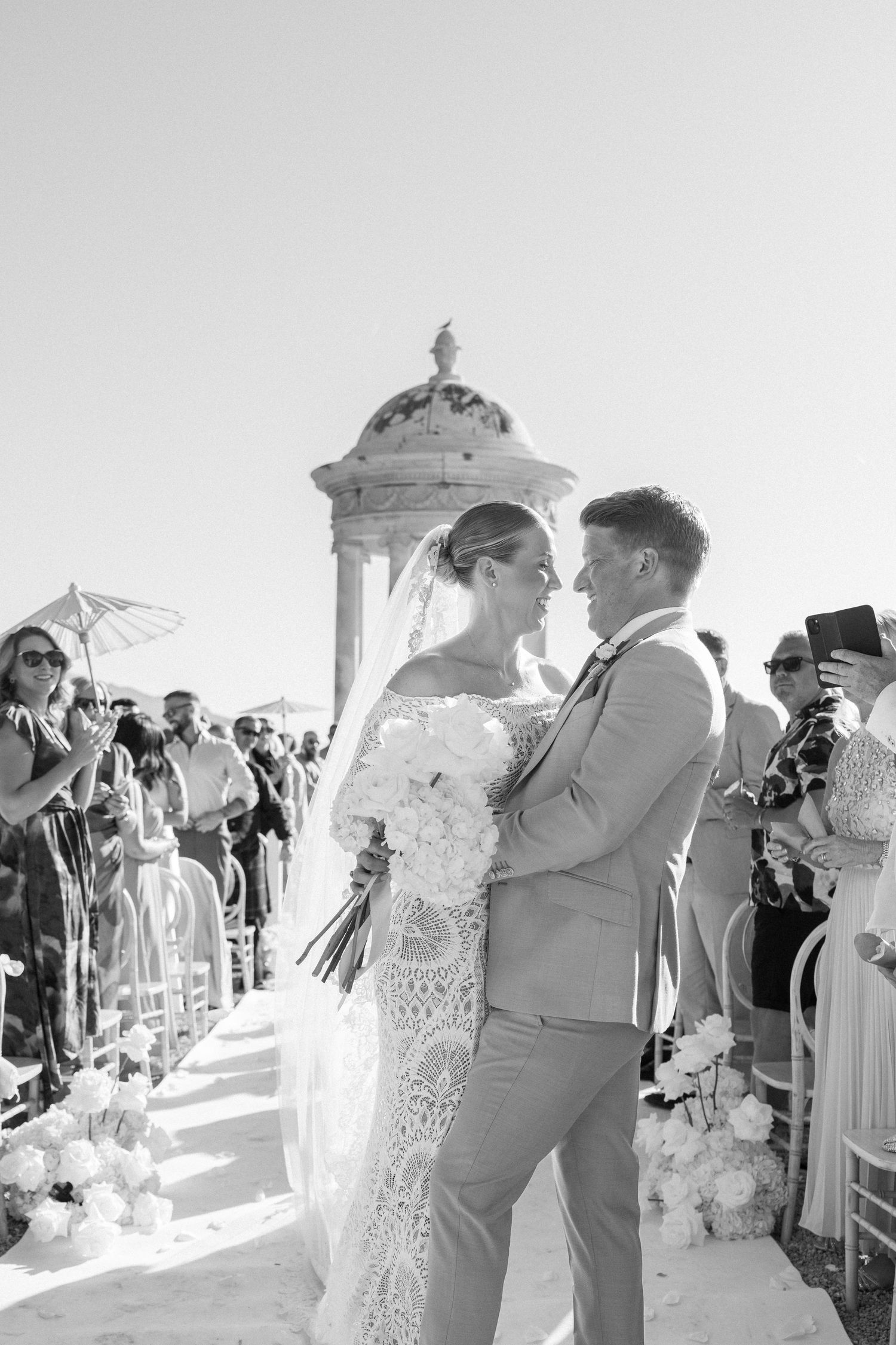 Wedding ceremony moments captured in black and white under an ornate gazebo.