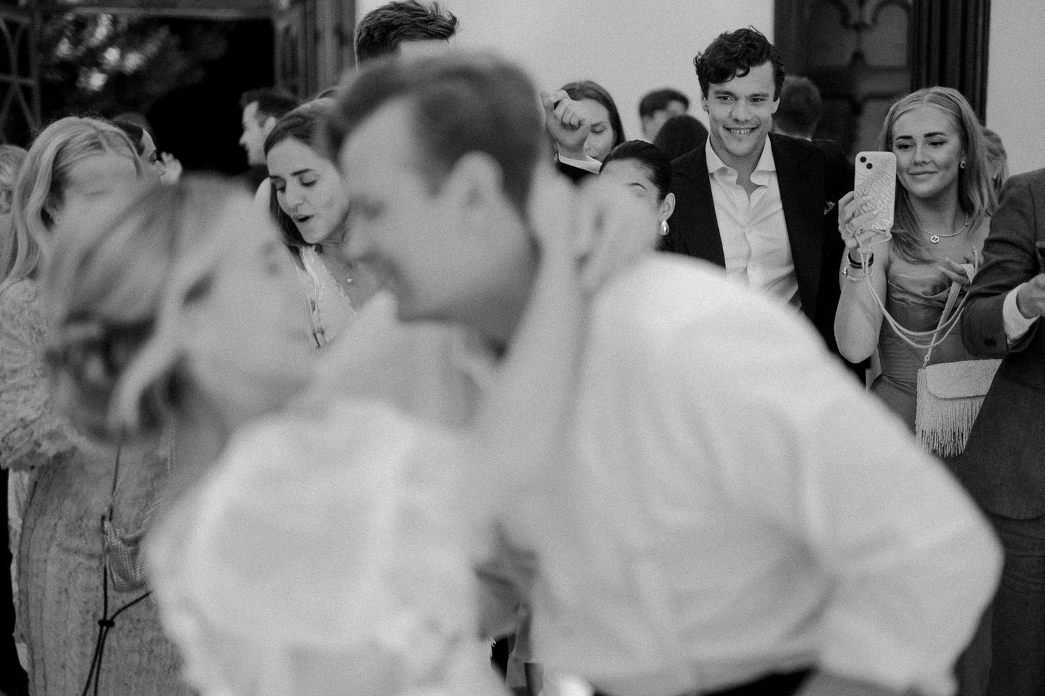 A joyful wedding celebration with guests dancing and mingling at an elegant indoor reception.