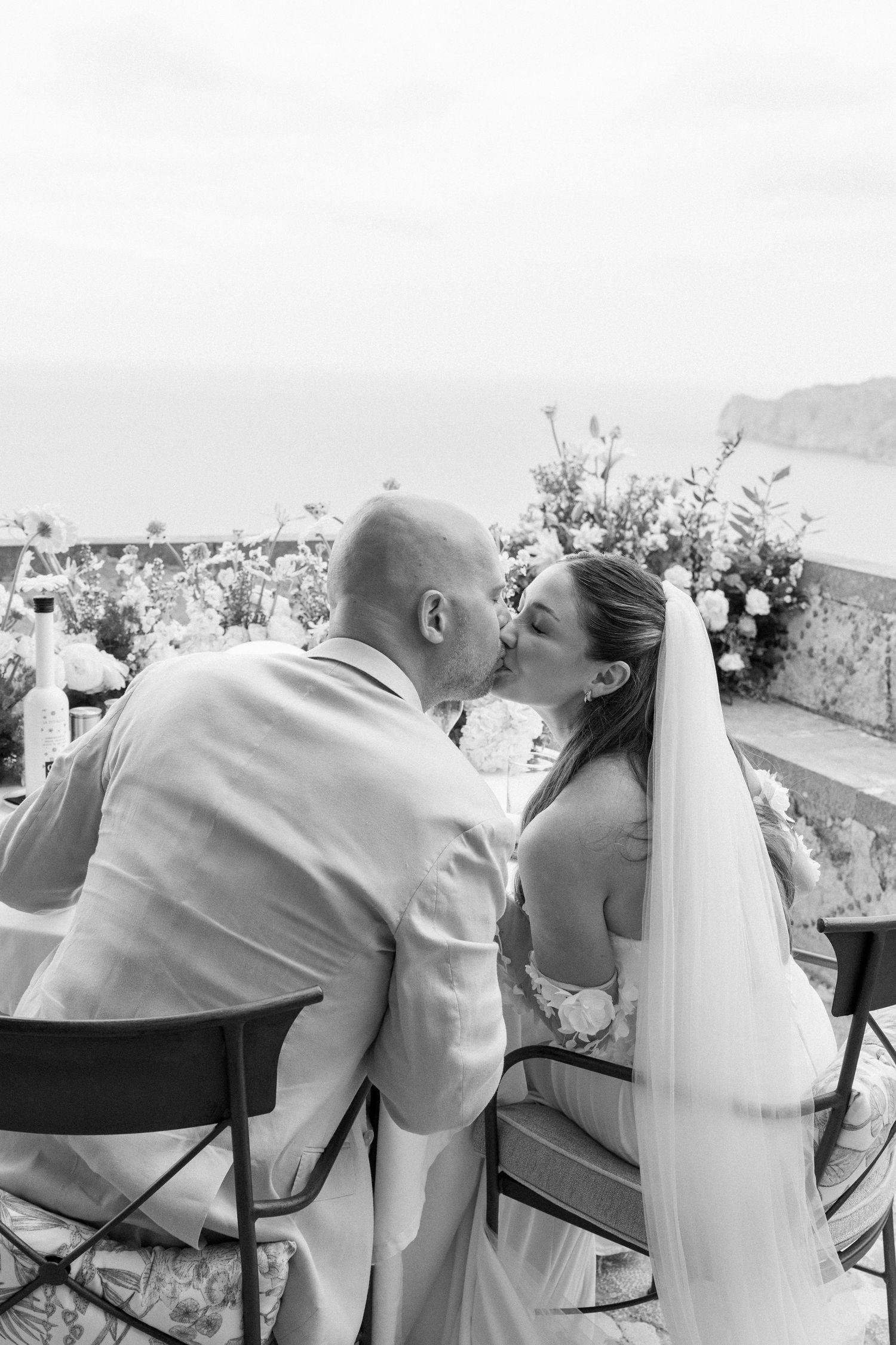 Wedding couple sharing intimate moments while seated at an outdoor reception.