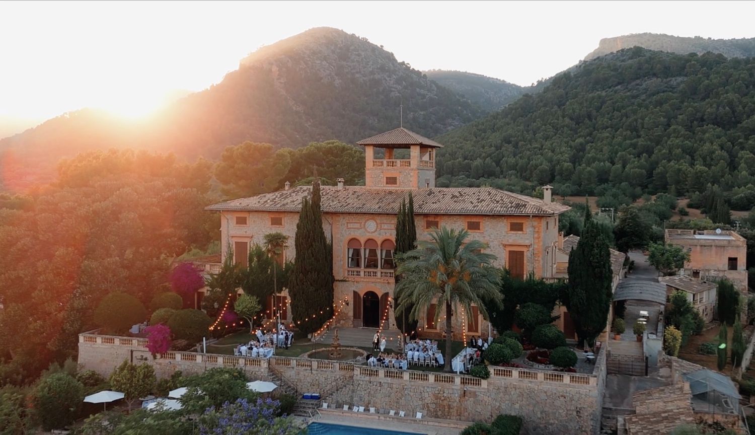 Aerial view of a stunning Mediterranean villa Son Togores nestled among lush green mountains at golden sunset.