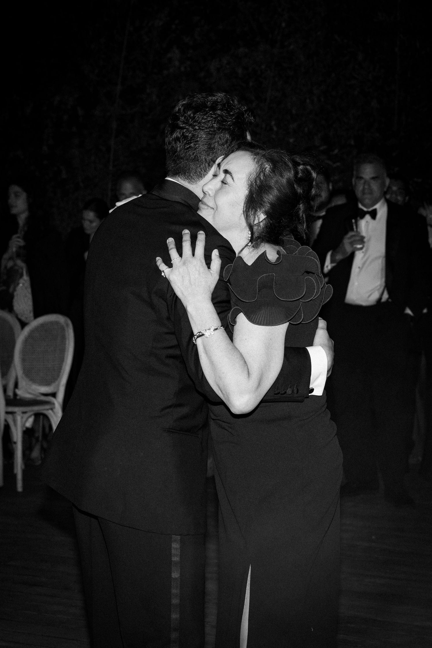 Black and white photo of a couple sharing a tender embrace while dancing at a formal evening event.