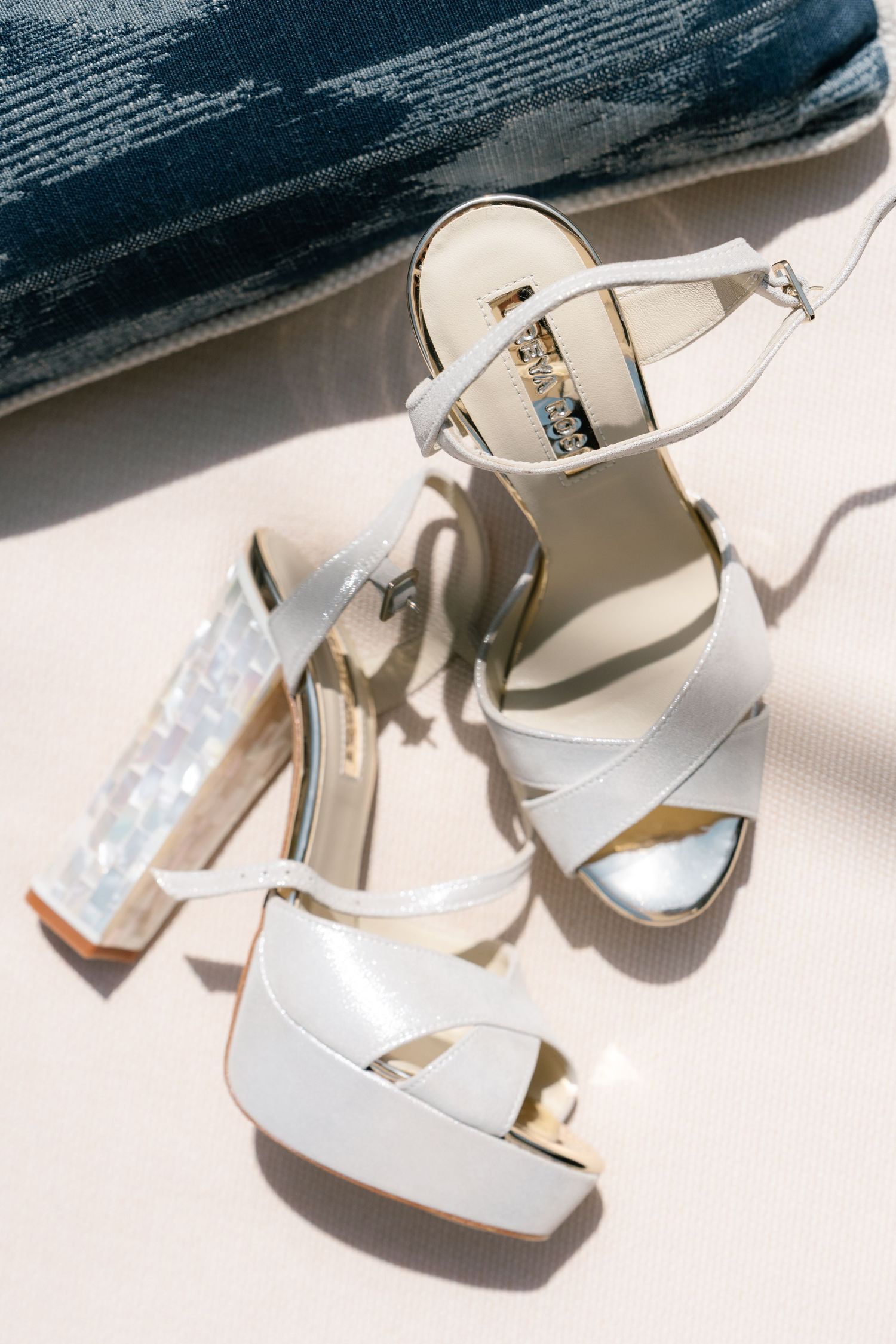 White strappy bridal heels with crystal embellishments against a light background.