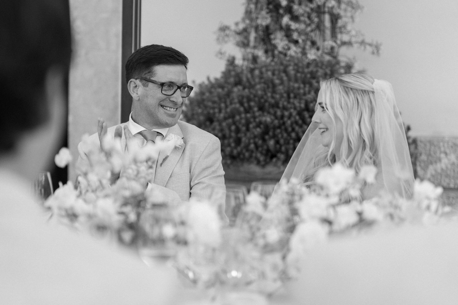 Black and white photo of wedding reception table with floral centerpieces.