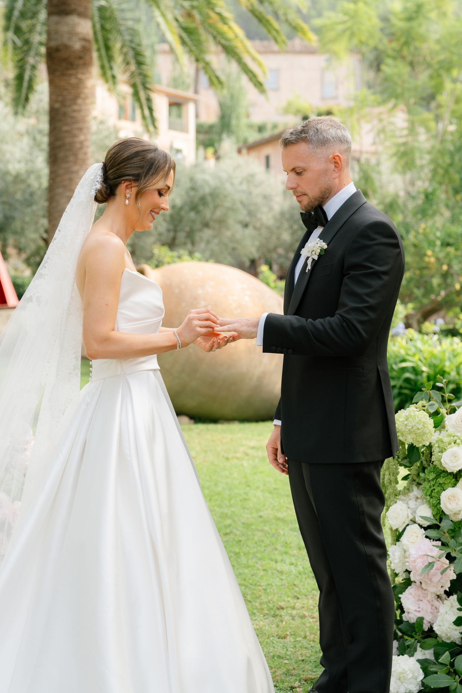 A couple exchanges rings during their outdoor garden wedding ceremony.